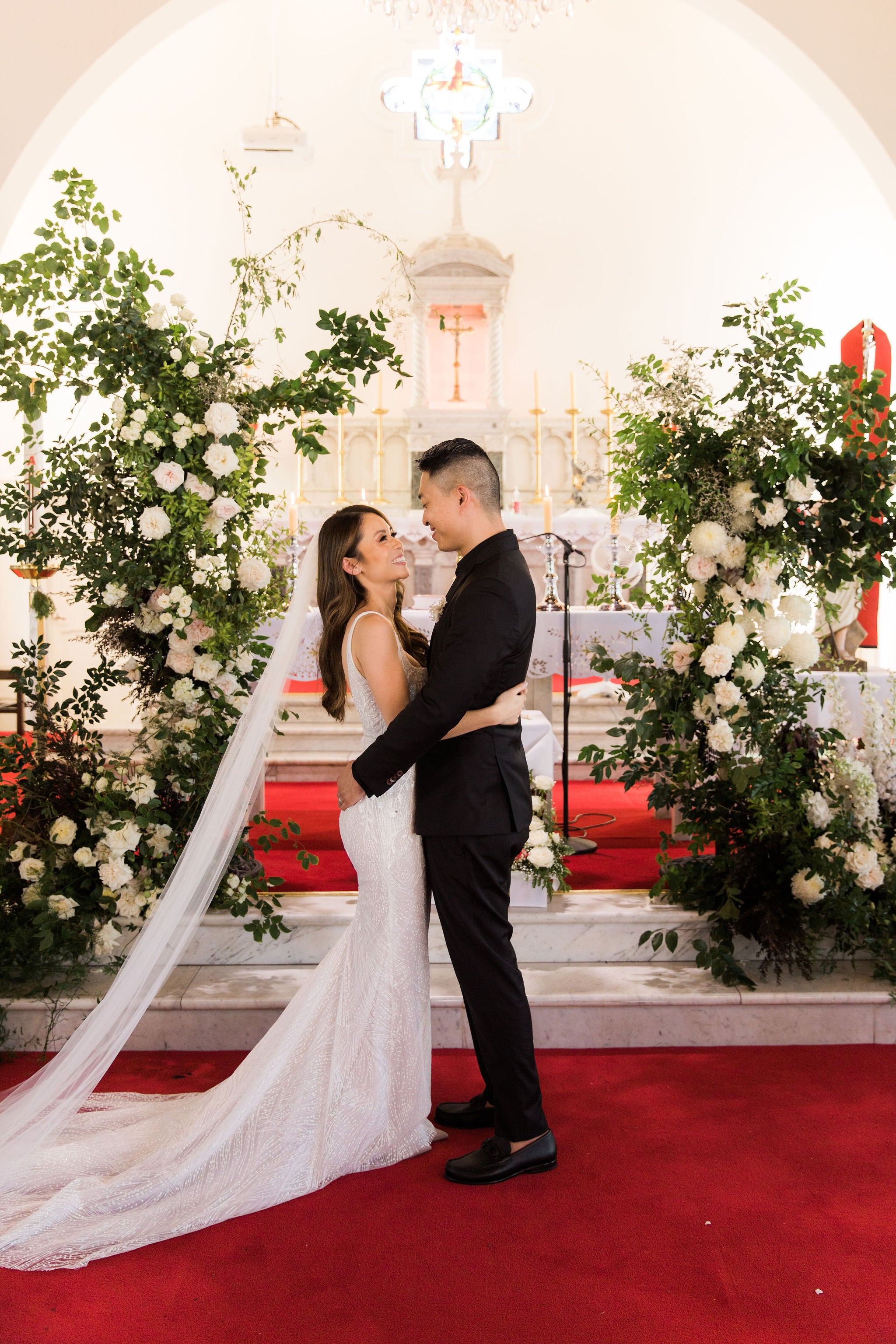 bride and groom hugging in front of alter at their wedding
