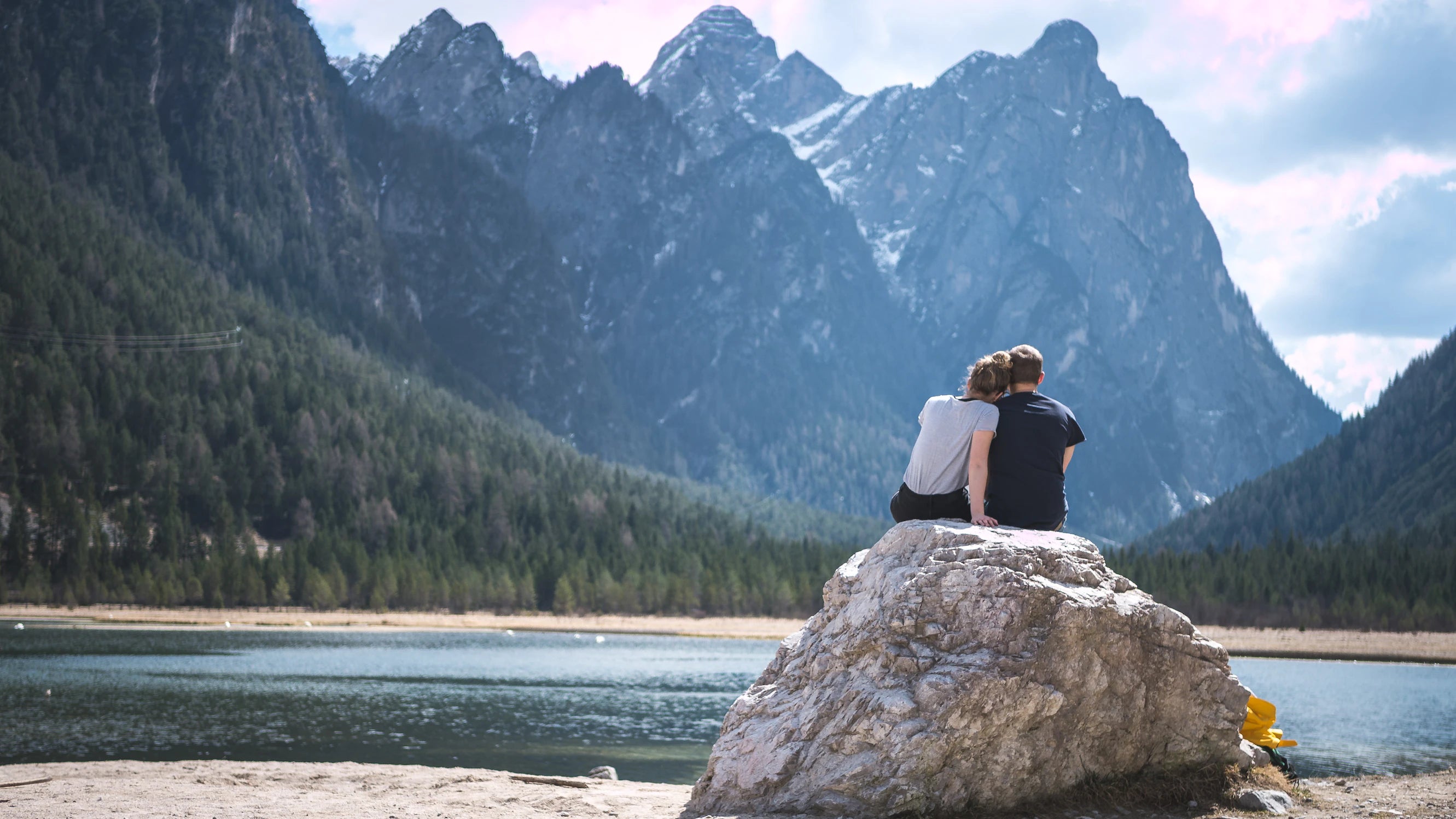 couple sitting together on a rock by lake