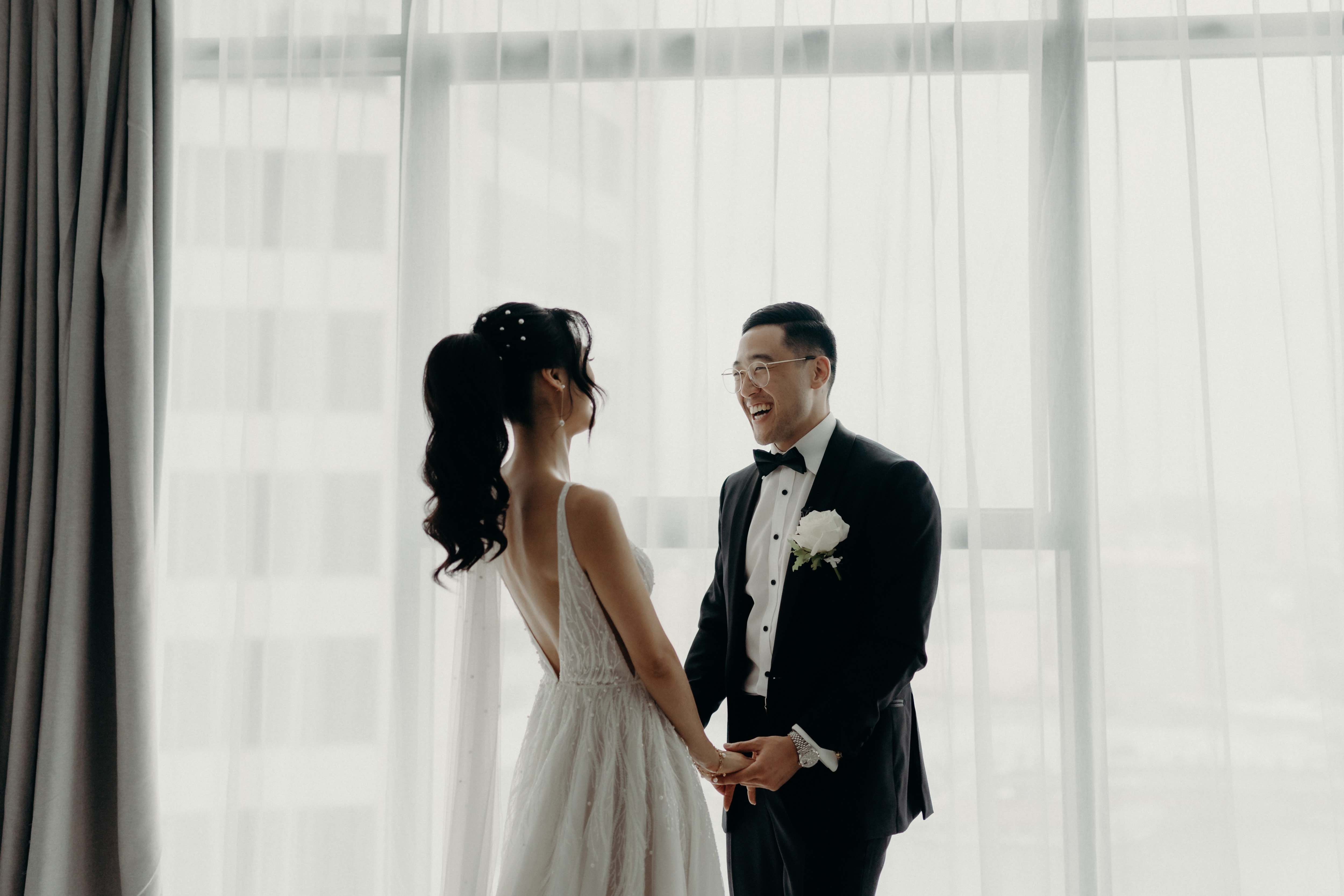 man in suit smiling holding hands with woman in wedding dress