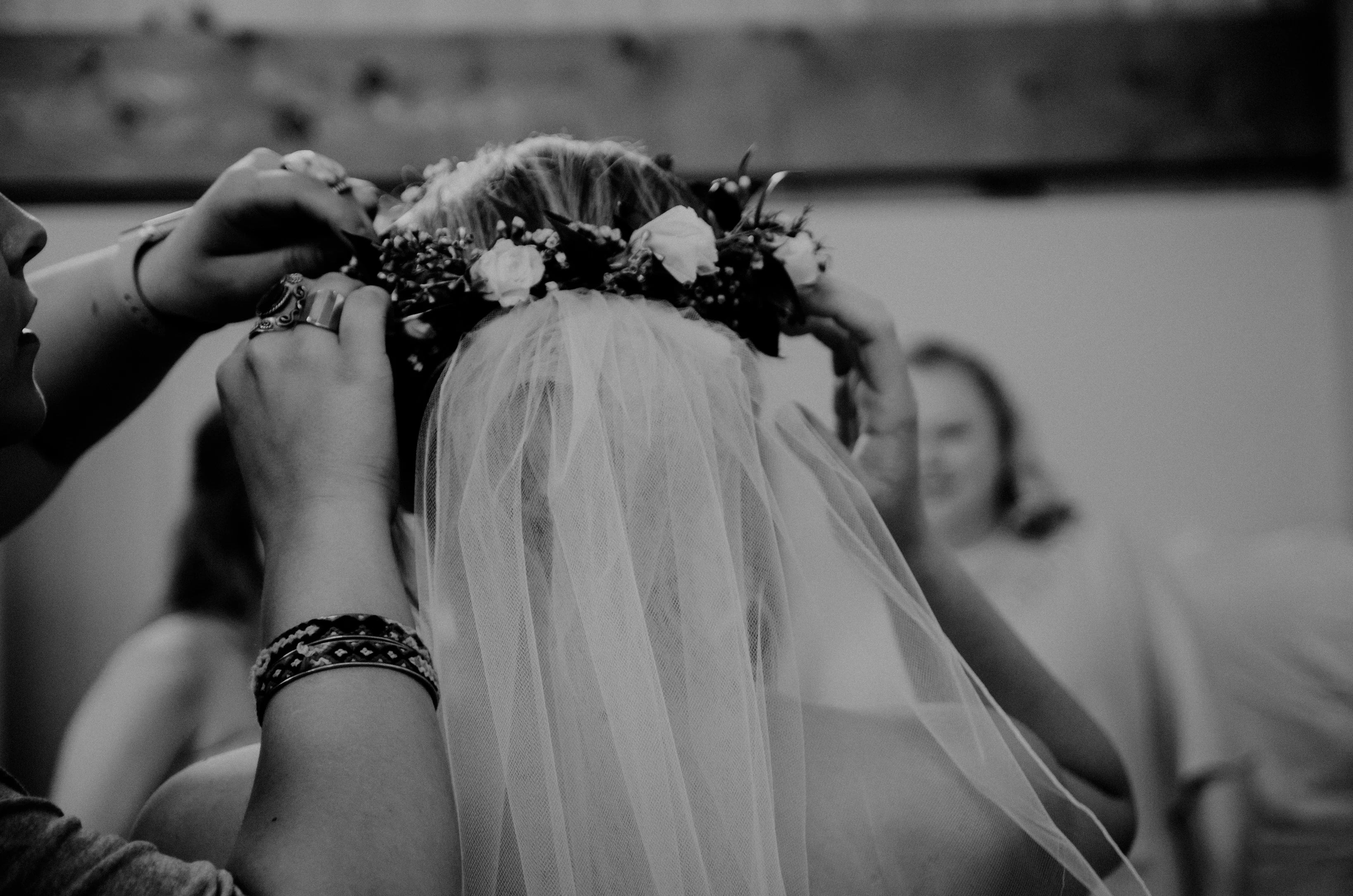 person helping bride put flower crown on head