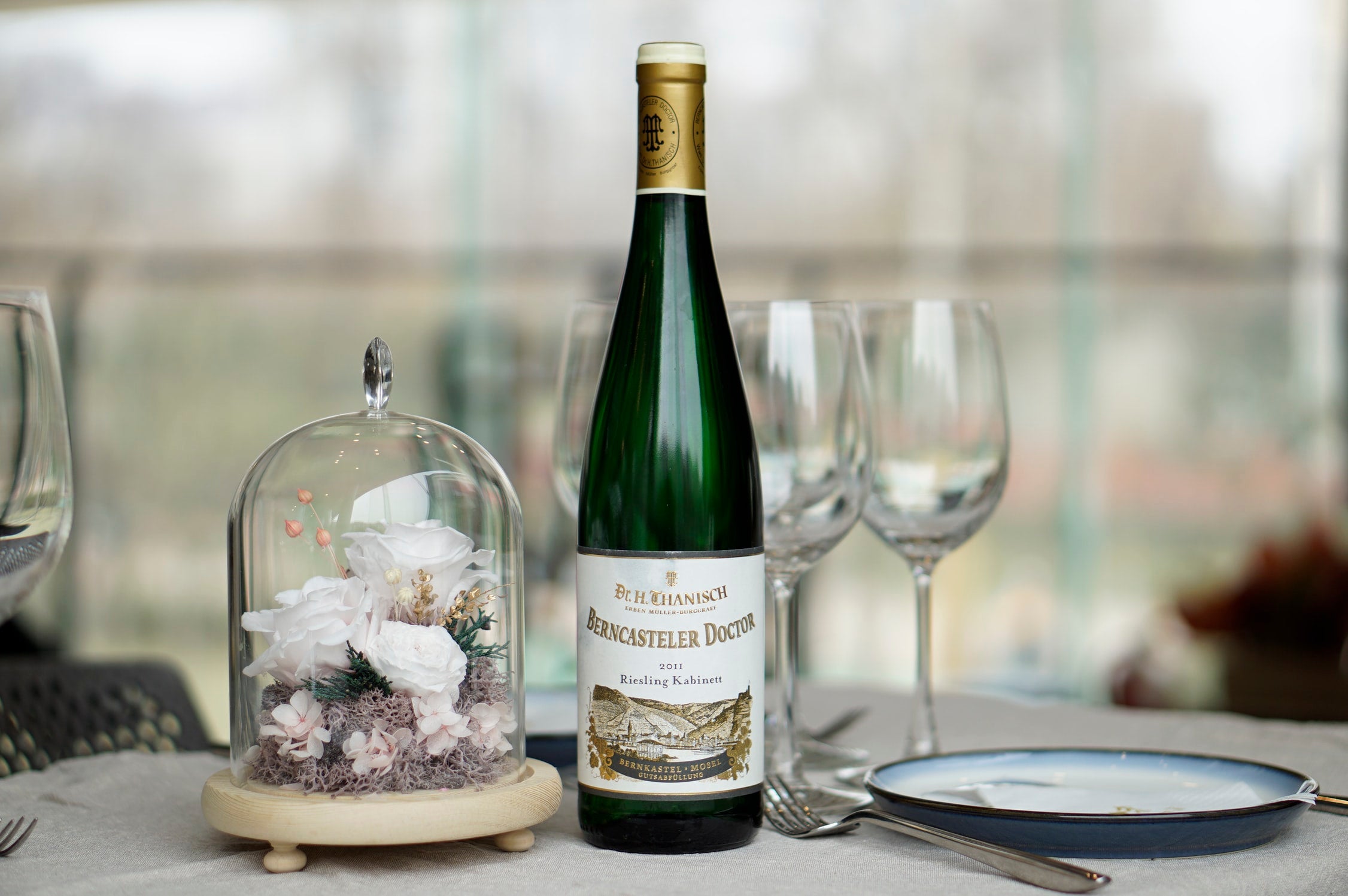 wine bottle with wine glasses and table settings at a wedding ceremony