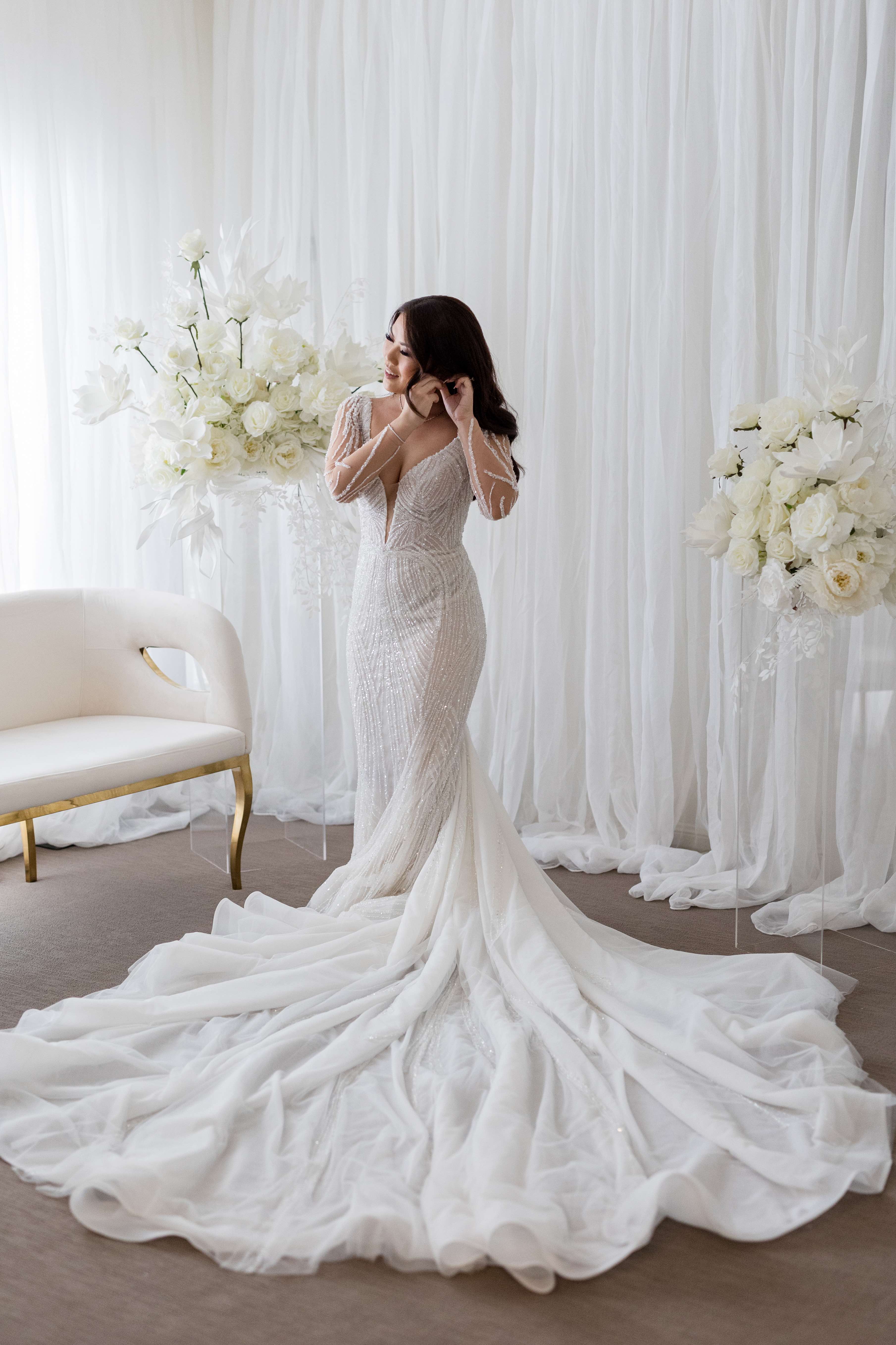 woman putting earrings on in her wedding dress