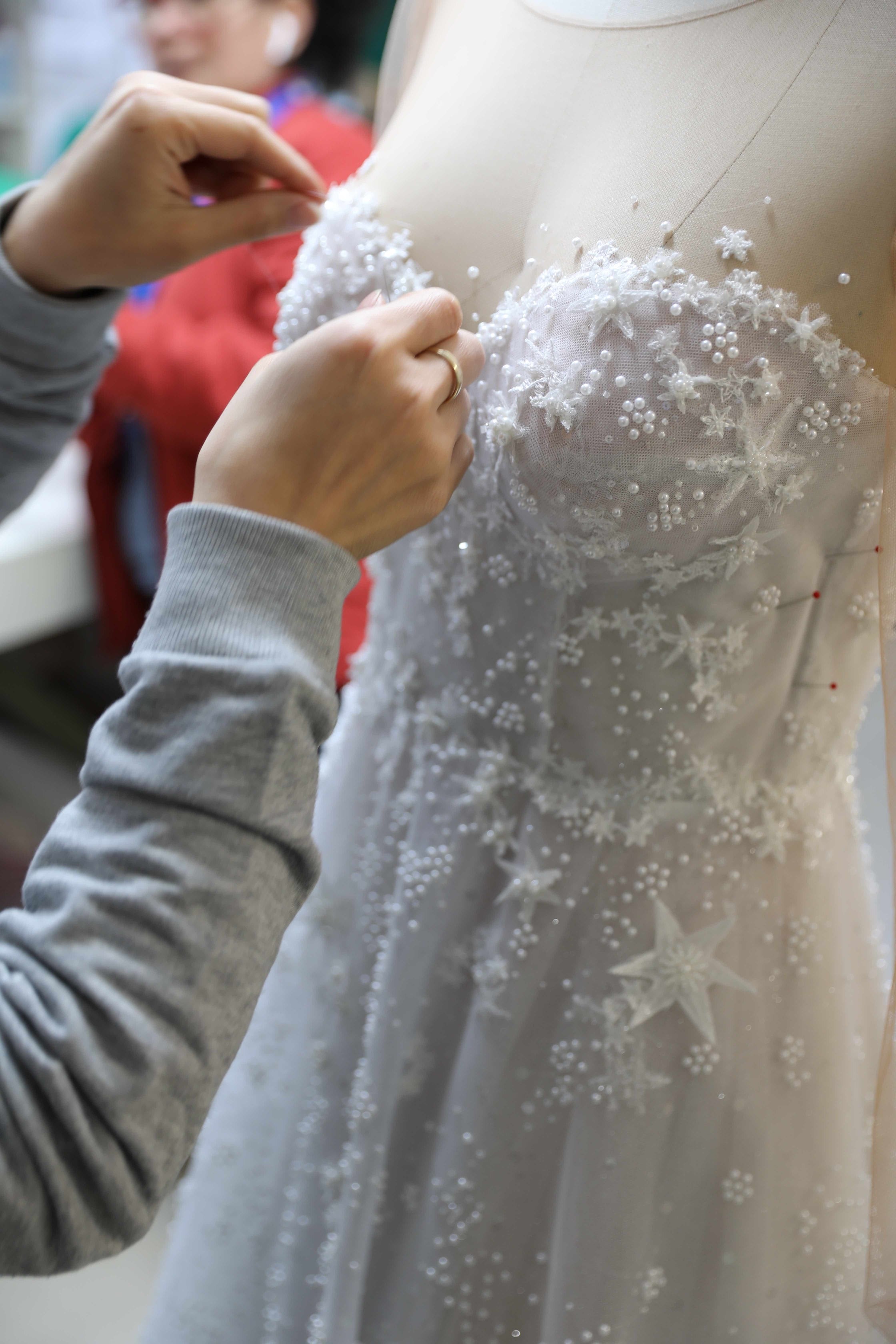 womans hands sewing cups on lace wedding dress