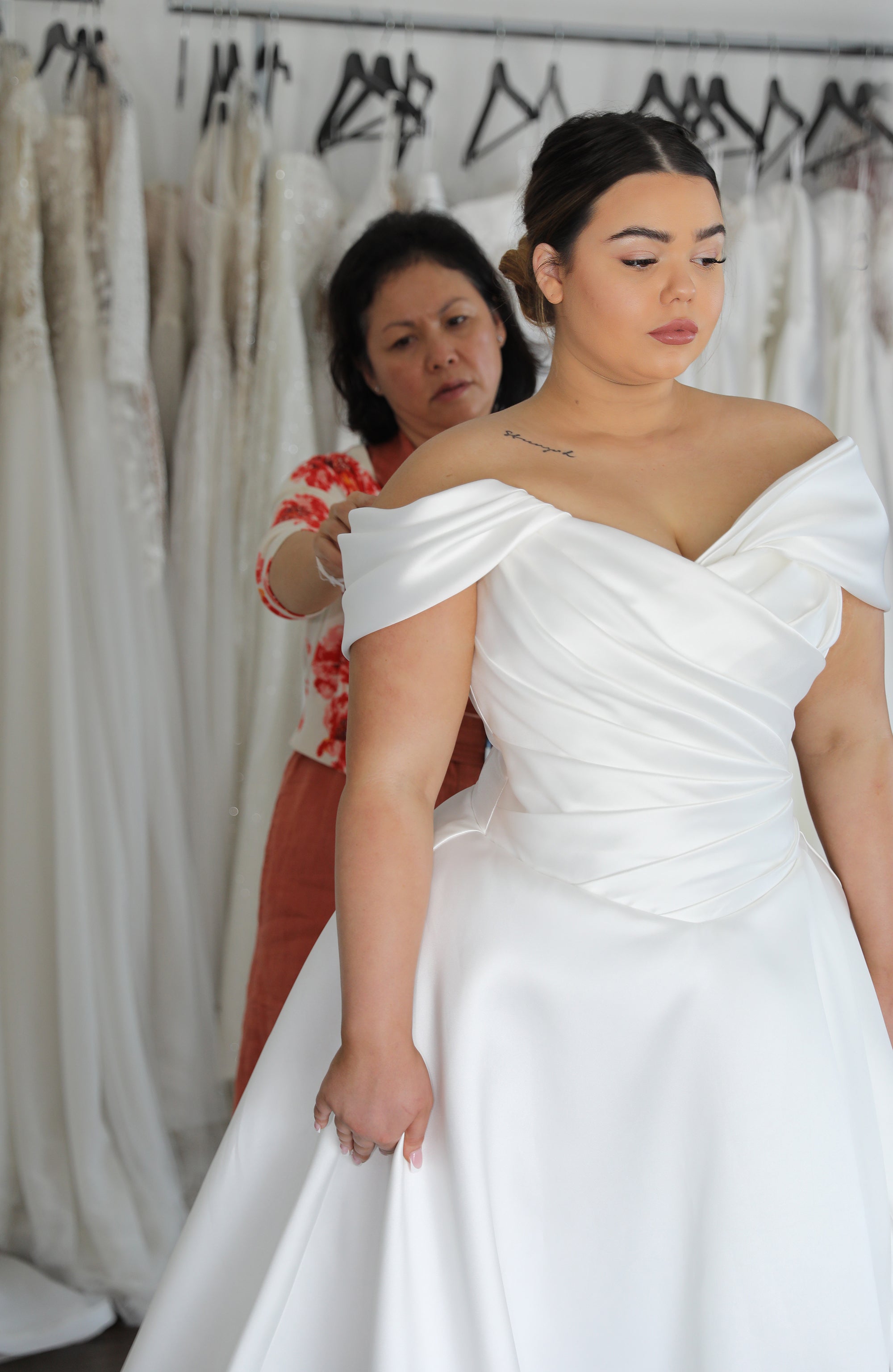 bridal designer helping bride into mikado wedding dress