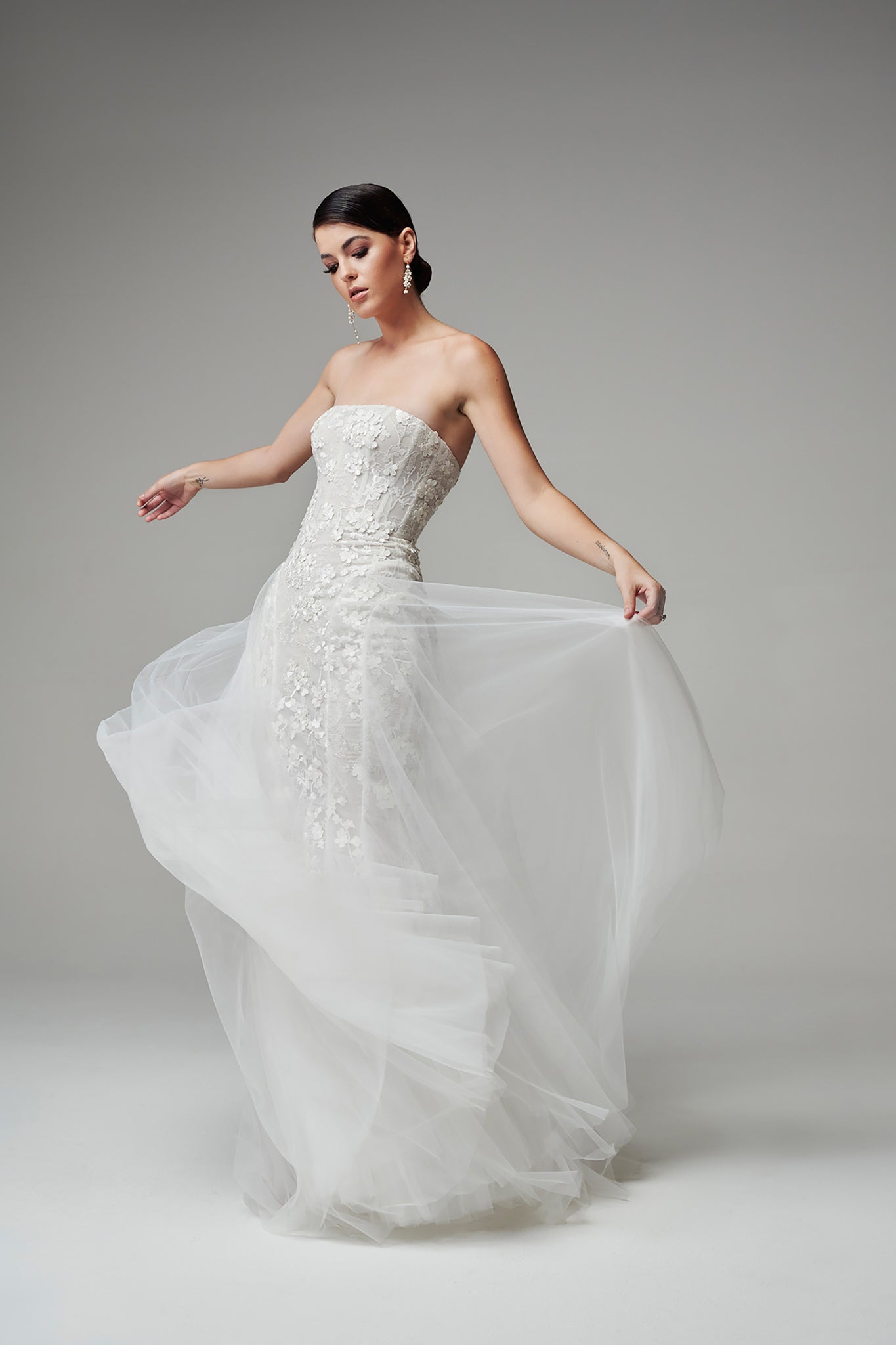 bride holding tulle skirt on strapless wedding gown