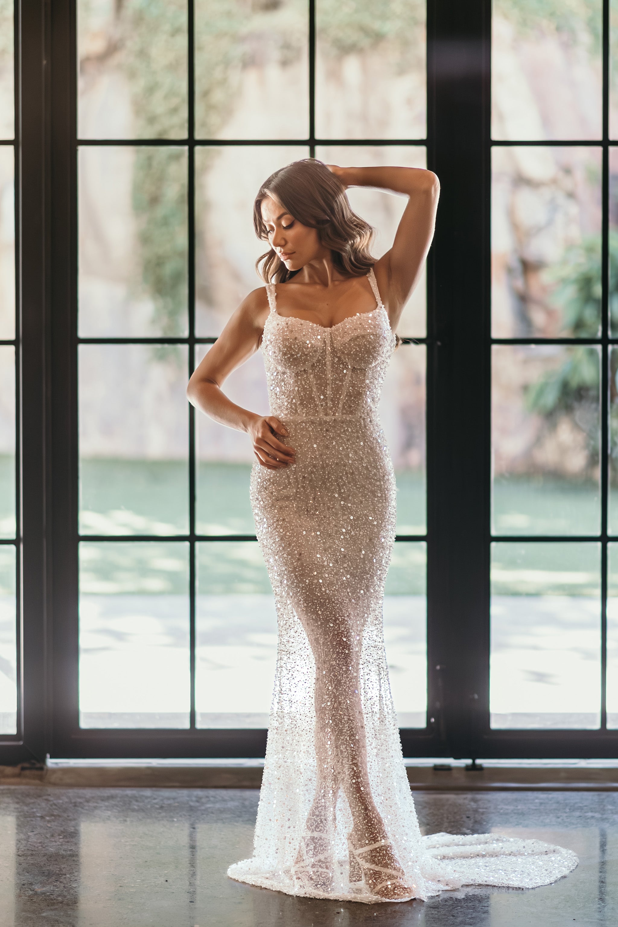 bride posing against window in her beaded wedding dress