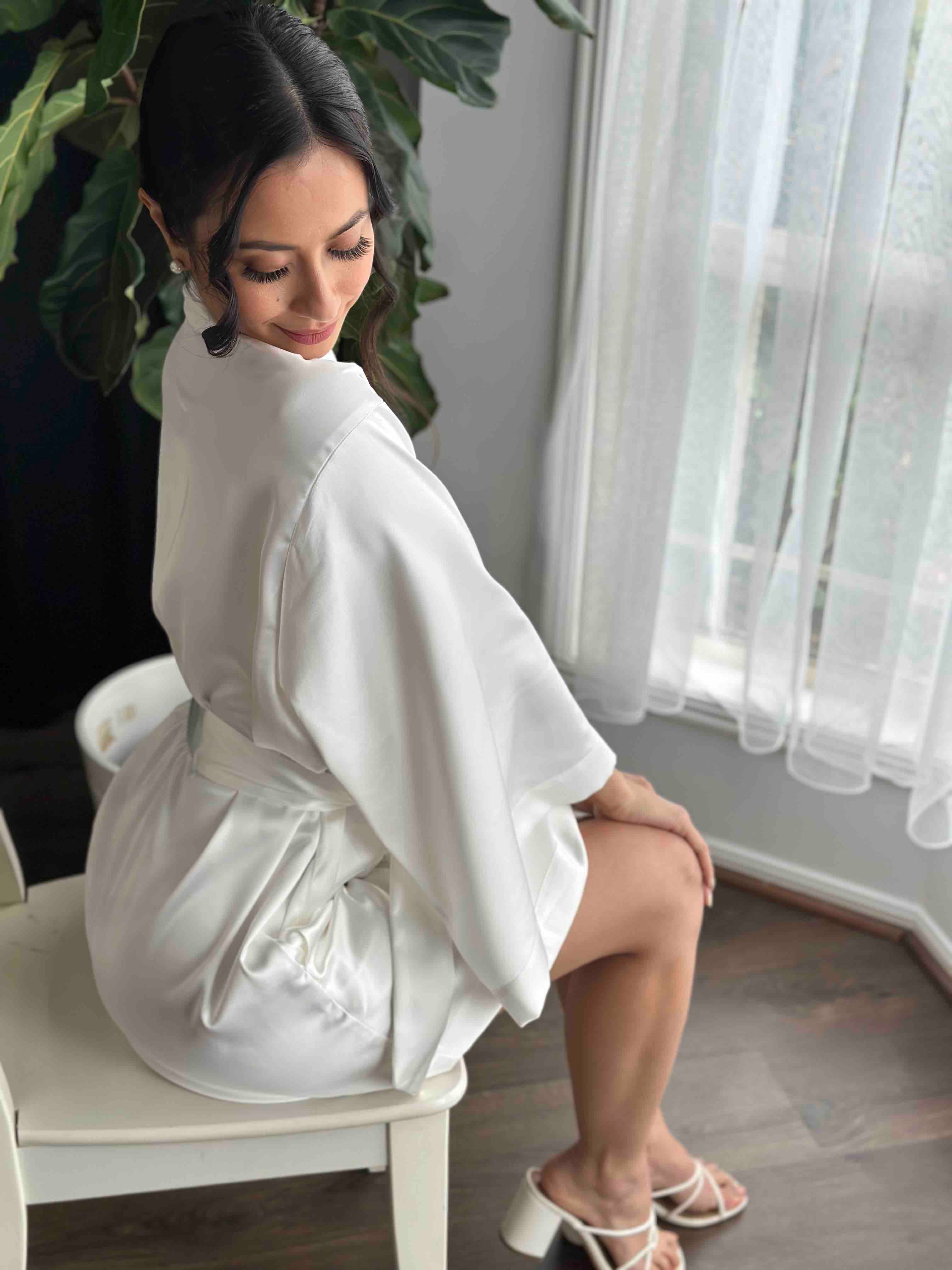 bride sitting down on white chair in robe