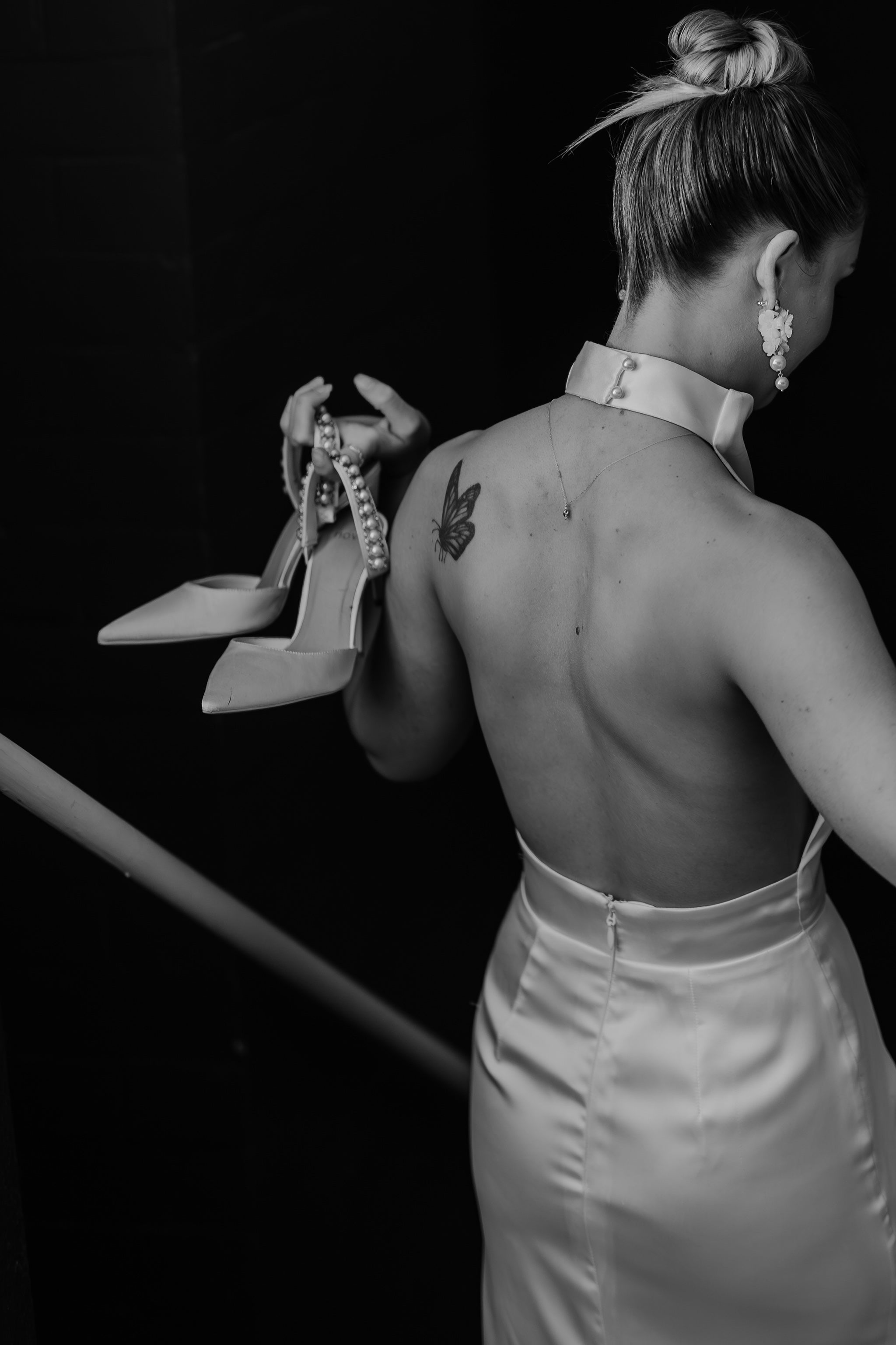 bride walking down stairs holding heels in wedding gown