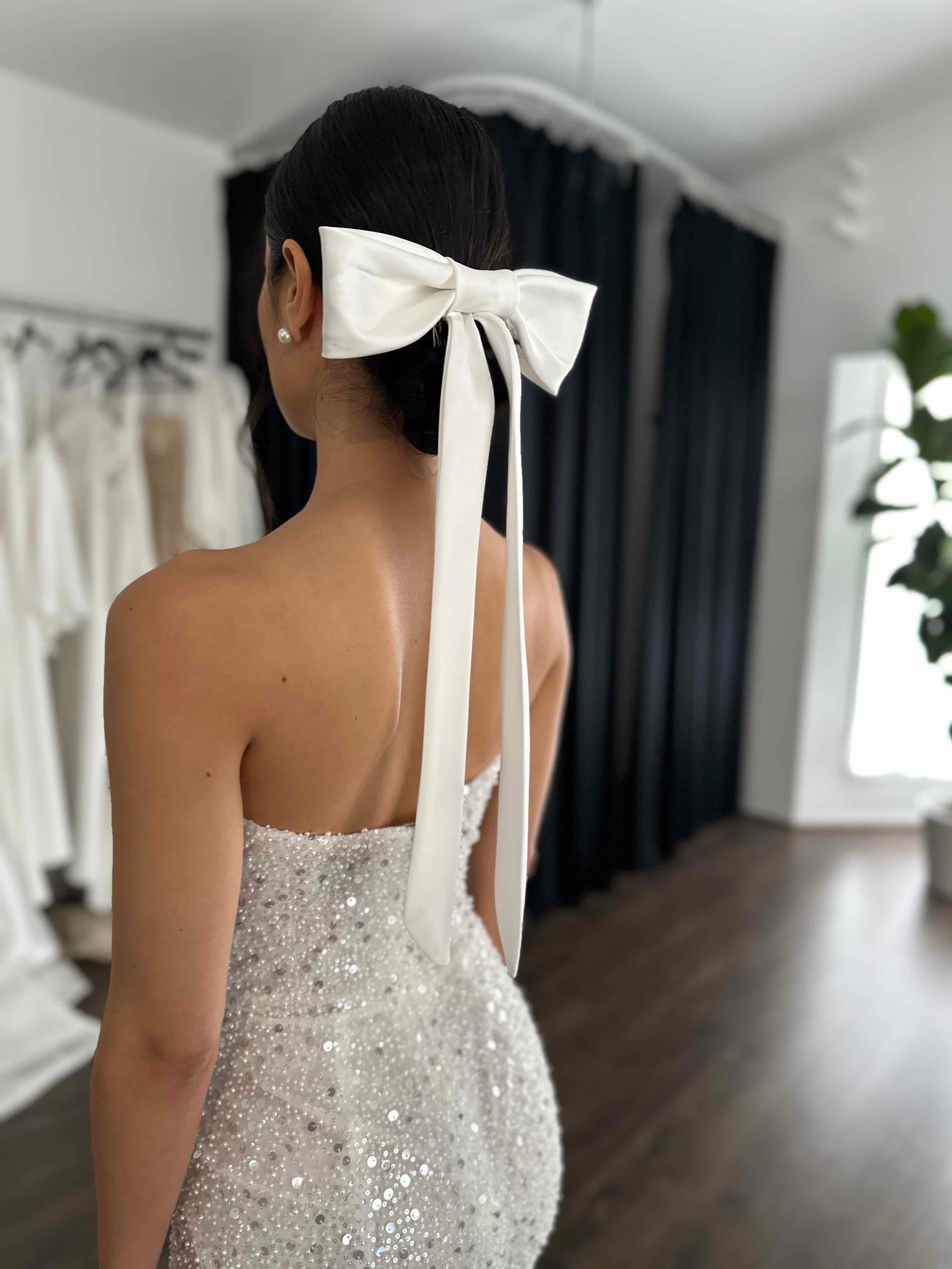 bride wearing sequin mini dress and bow tie clipped into her hair