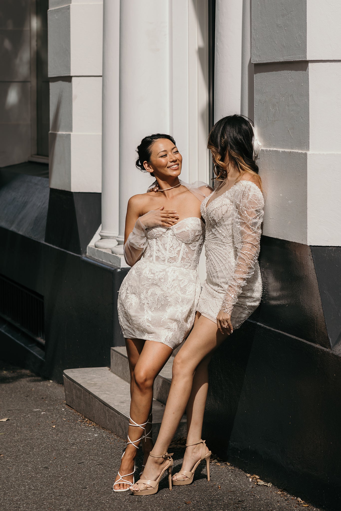 brides hug against wall in mini dresses