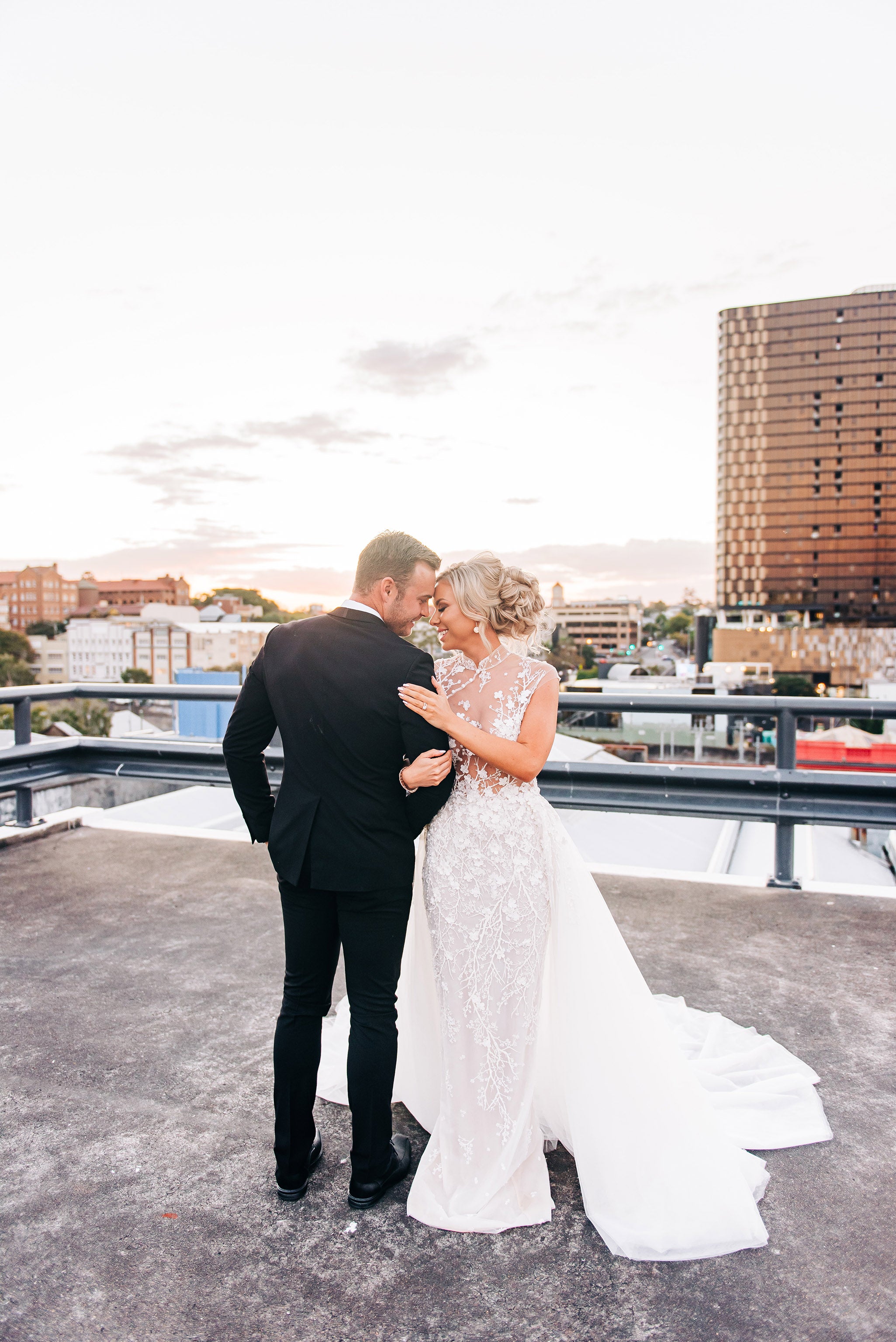 husband and wife cuddling on city rooftop