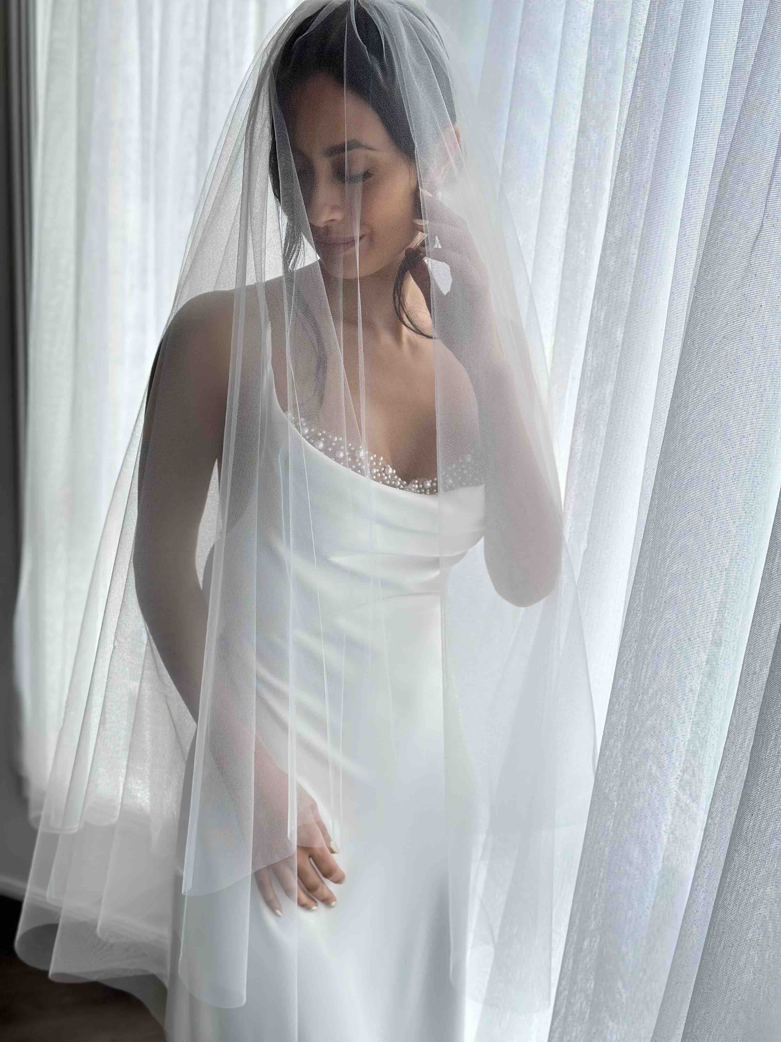 short bridal veil with blusher on woman wearing wedding slip with pearl inserts