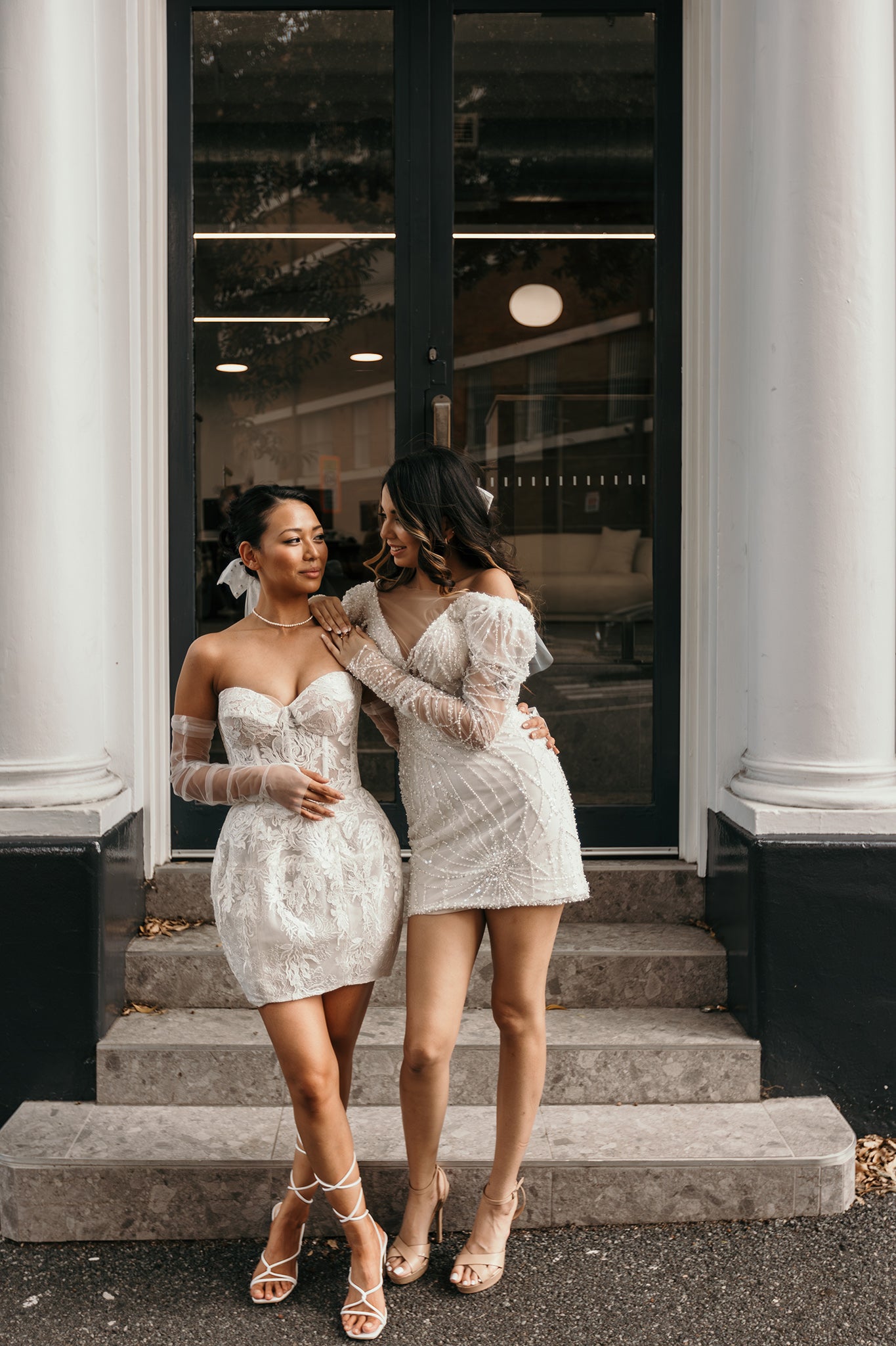 two brides in mini wedding dress hugging