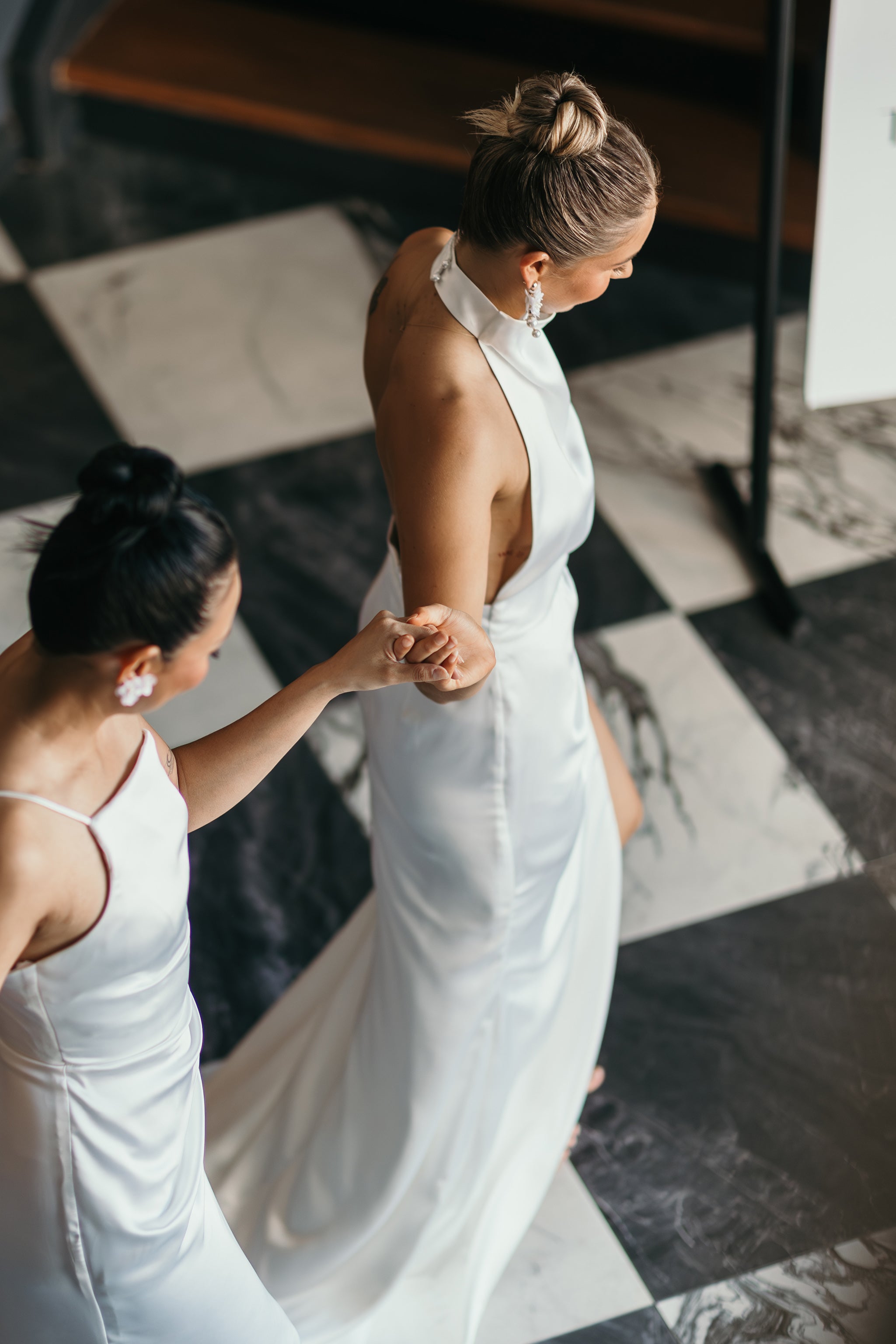 two brides in white wedding gowns on checkered floor