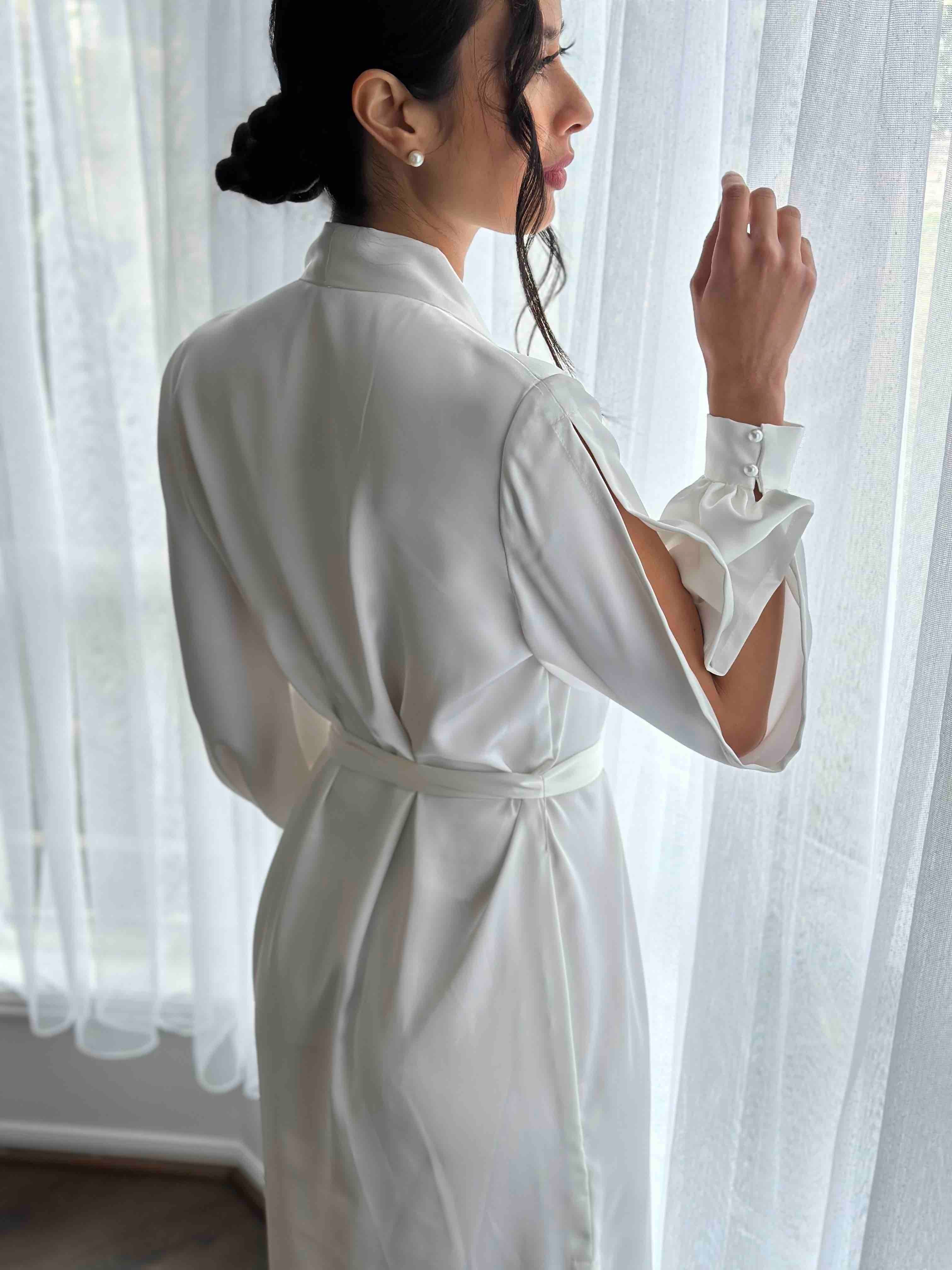woman peering out window in a dressing robe