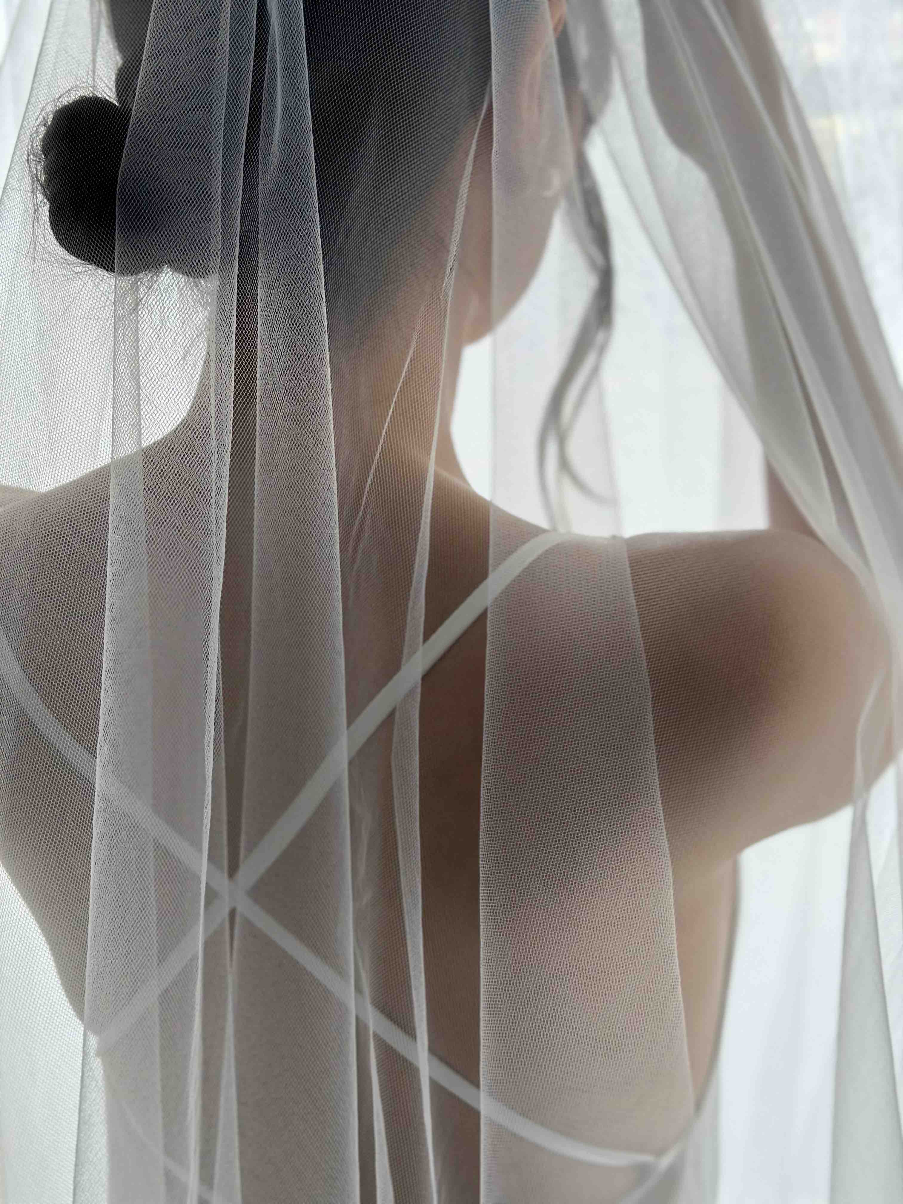 woman wearing tulle veils nd dress with cross back ties