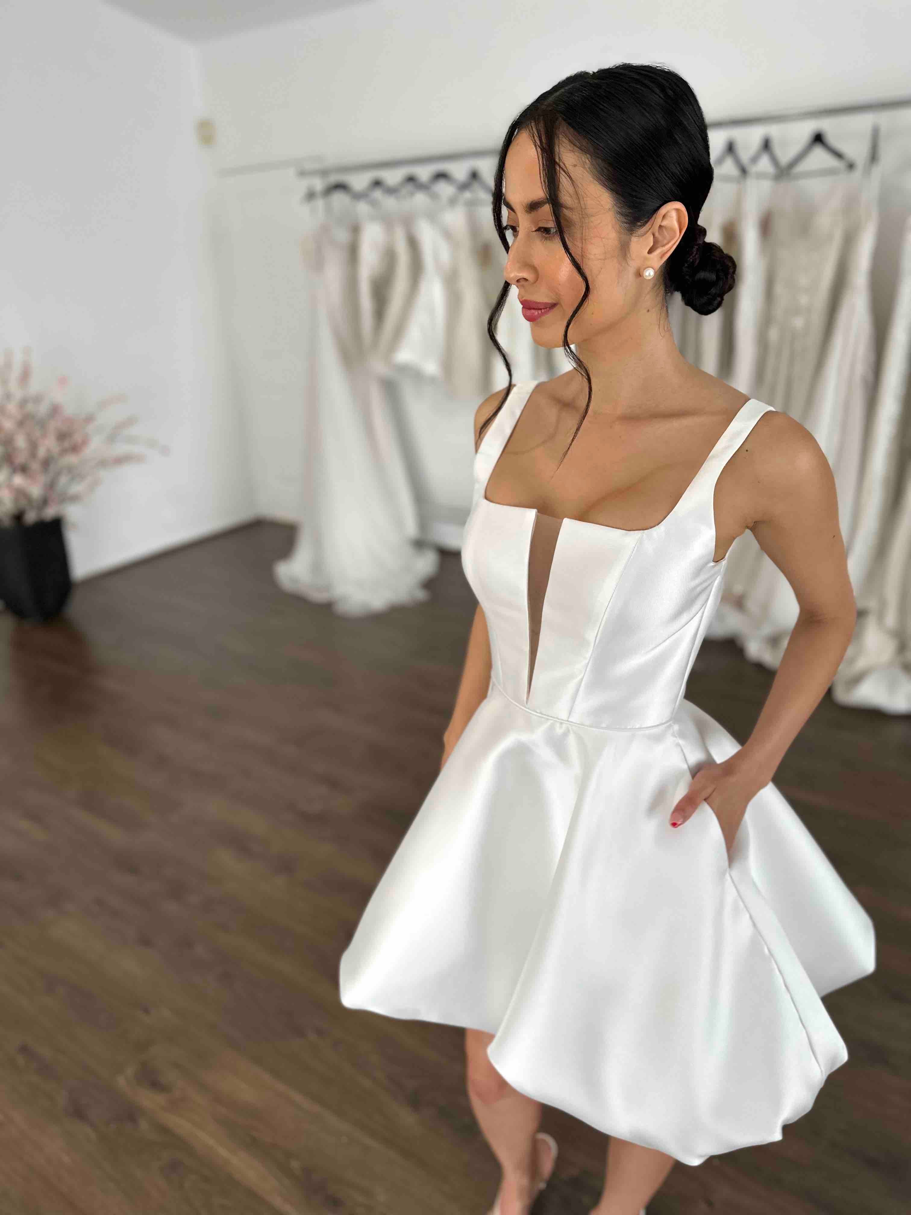 woman with black hair and pearl earrings in white mini dress