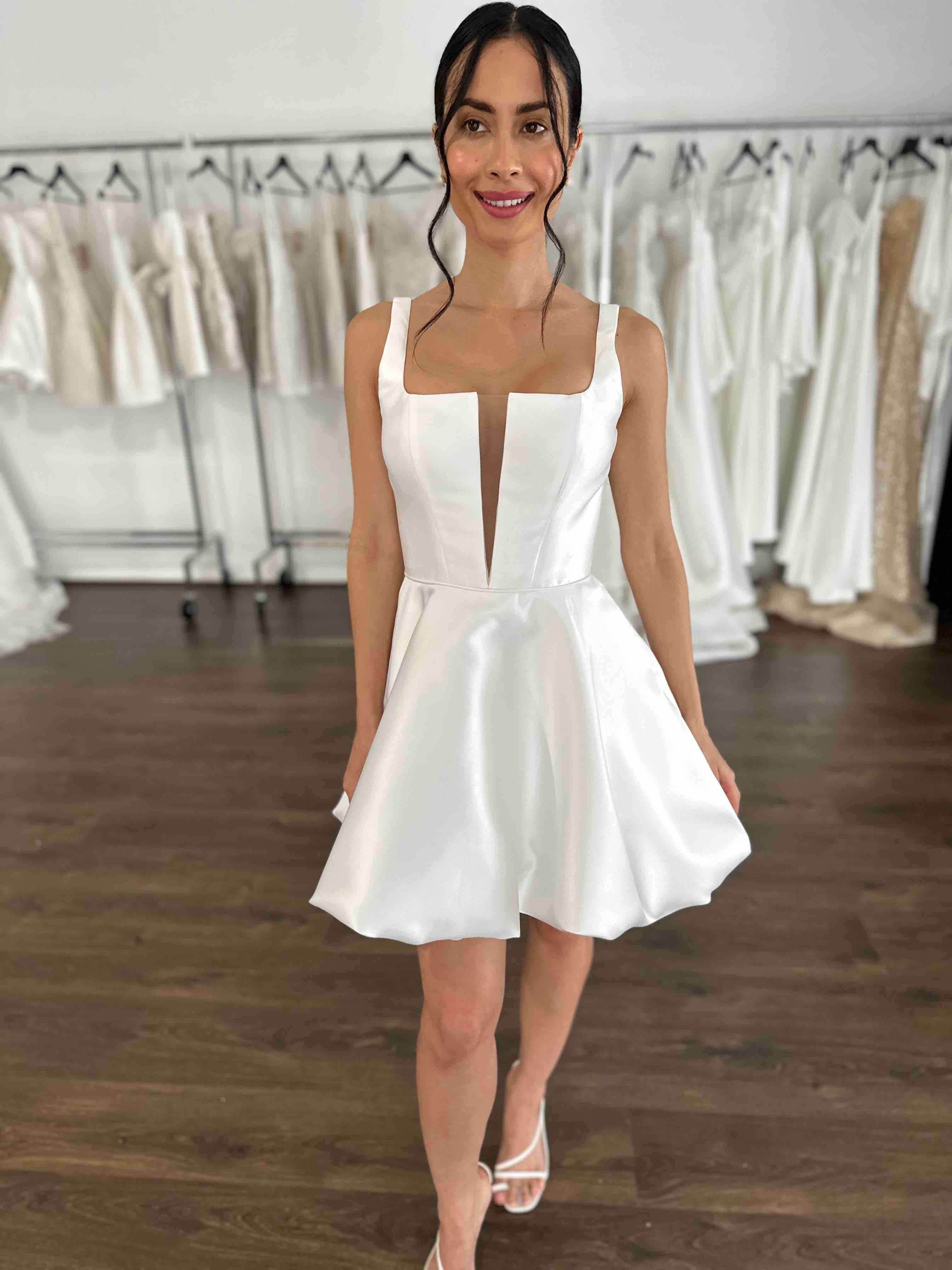 woman with black hair and pink lipstick smiling wearing white mini dress