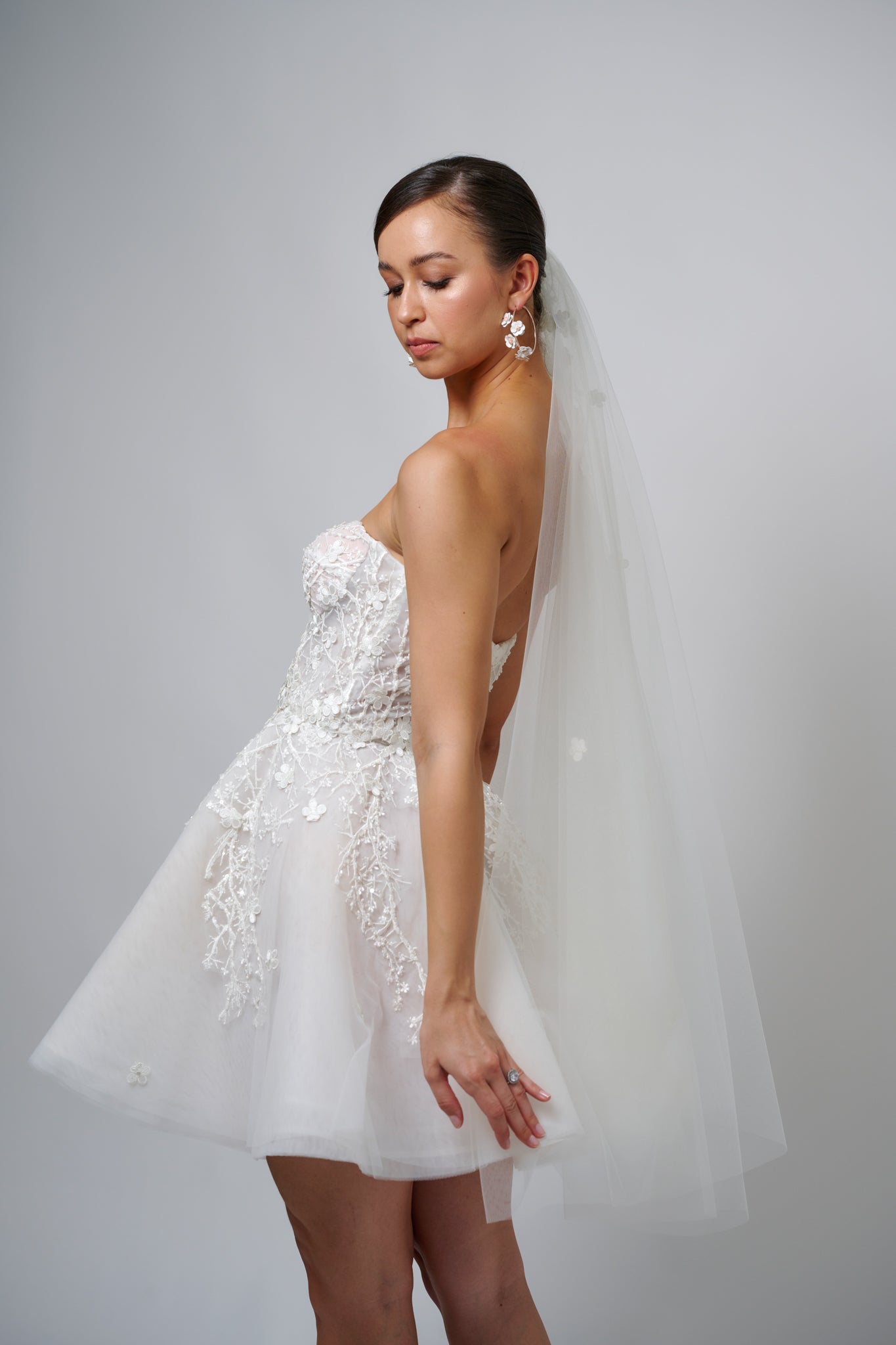 brunette woman with veil in hair and hoop earrings wearing white mini elopement wedding gown