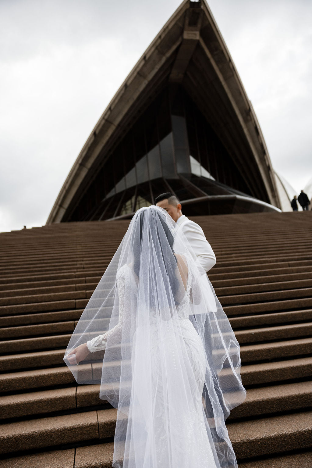 husband and bride on staircase wearing veil