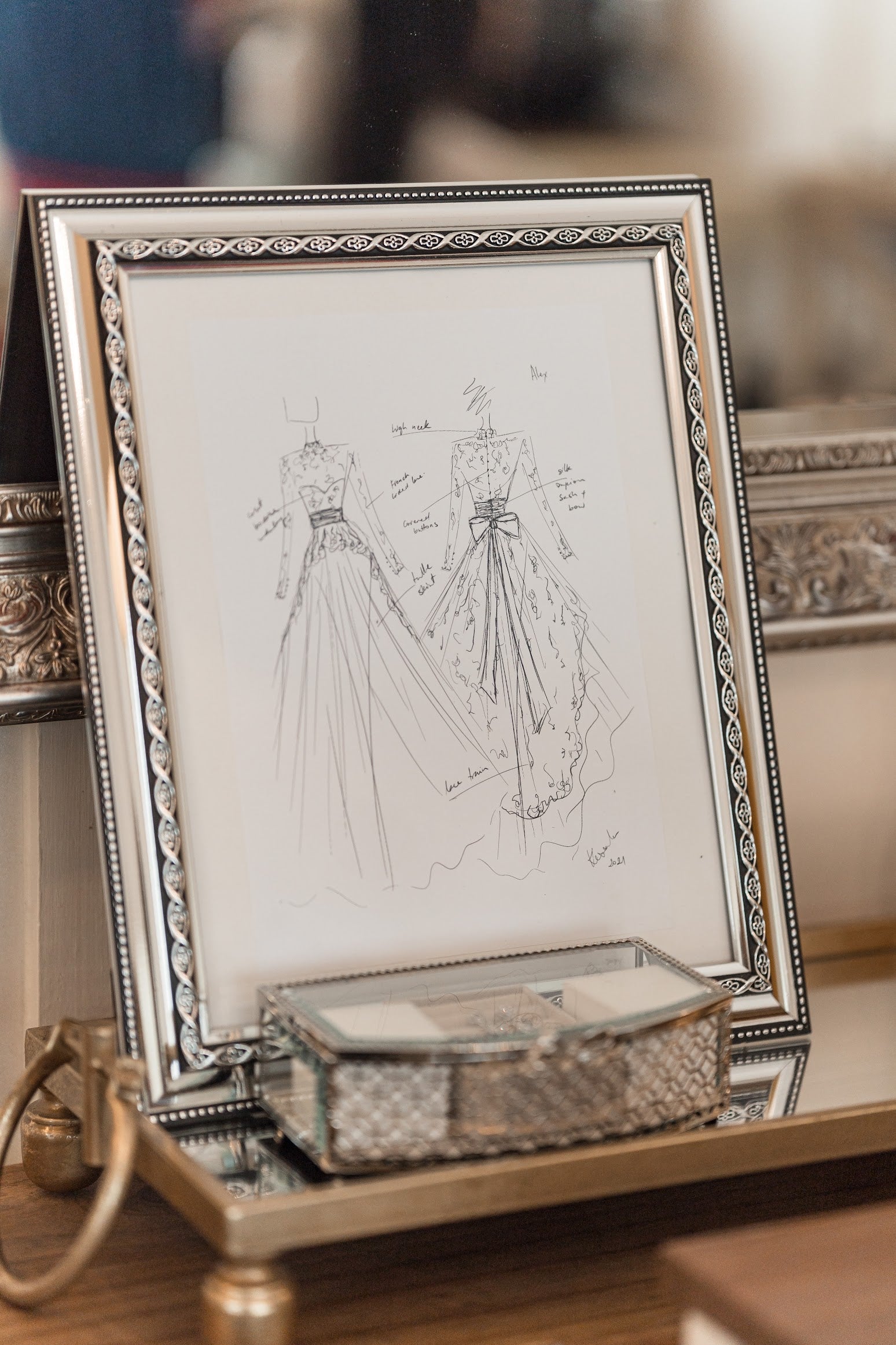 sketch of a wedding dress on paper inside a frame displayed on table