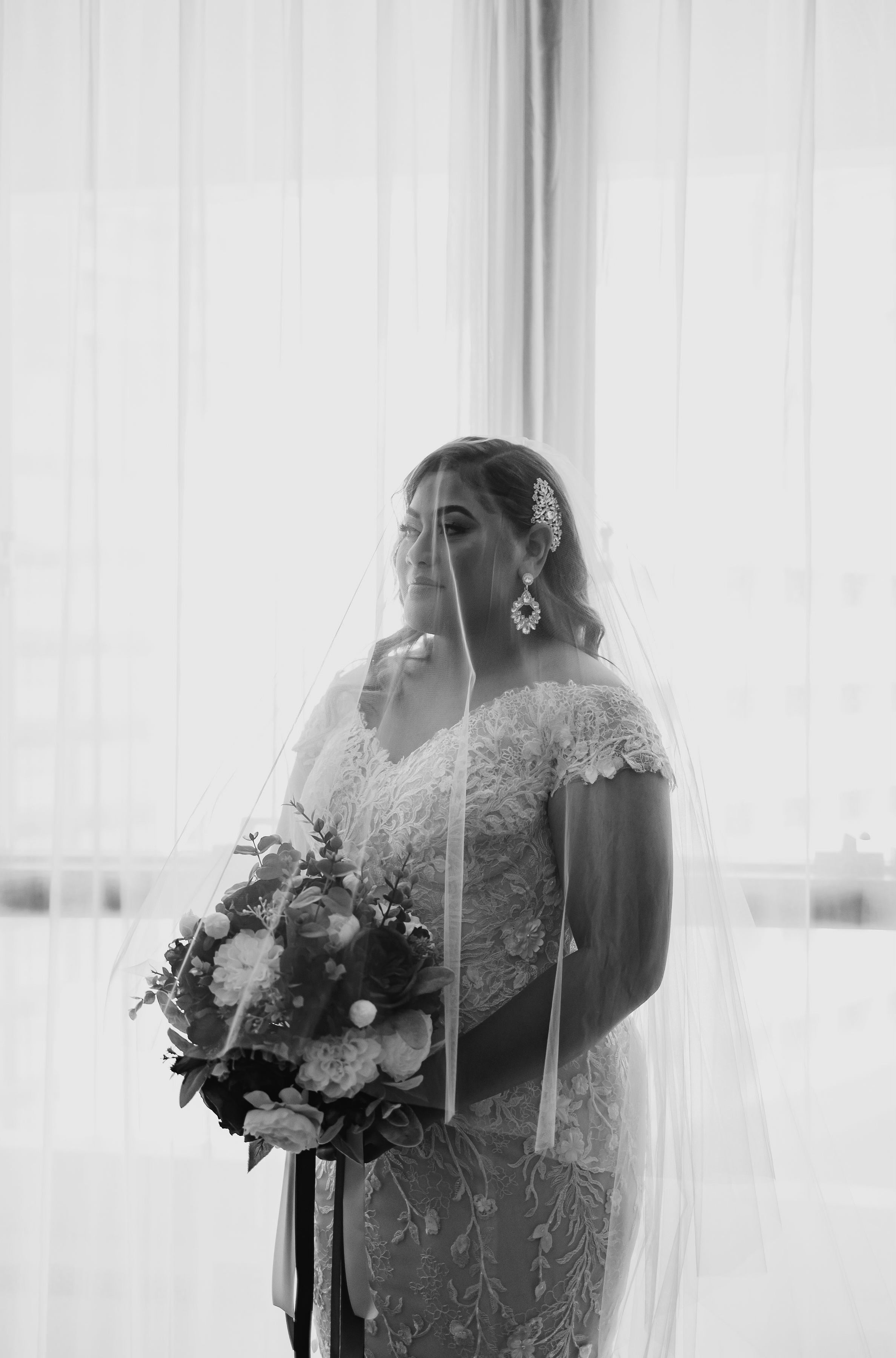 woman wearing wedding dress and tulle veil holding bouquet
