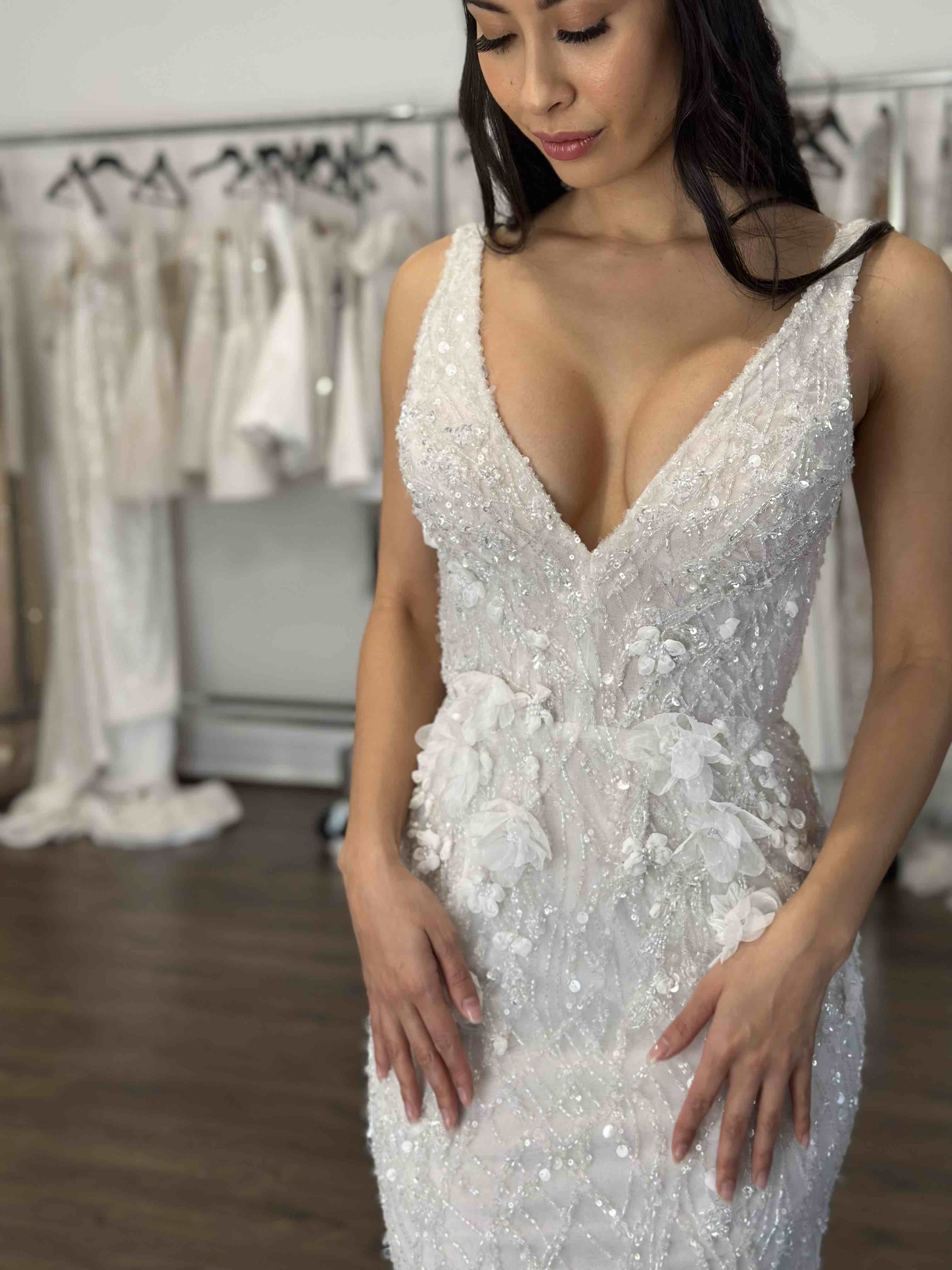 woman with hands at her side wearing beaded gown at bridal store