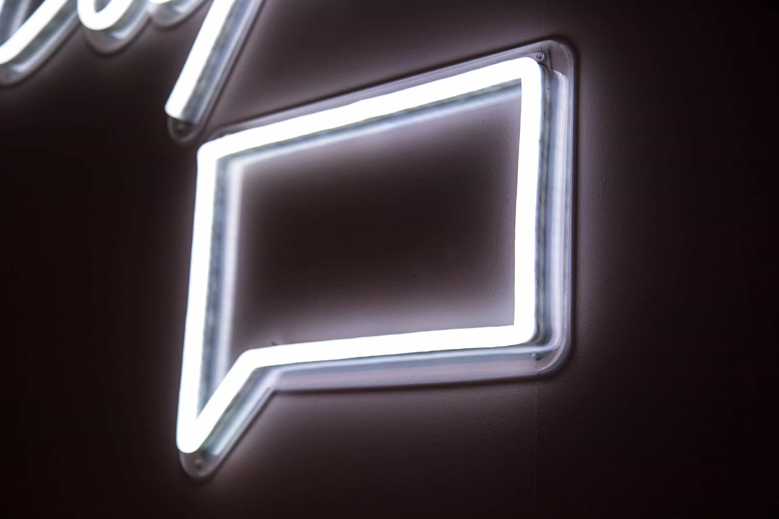 a neon light sign of a chat box