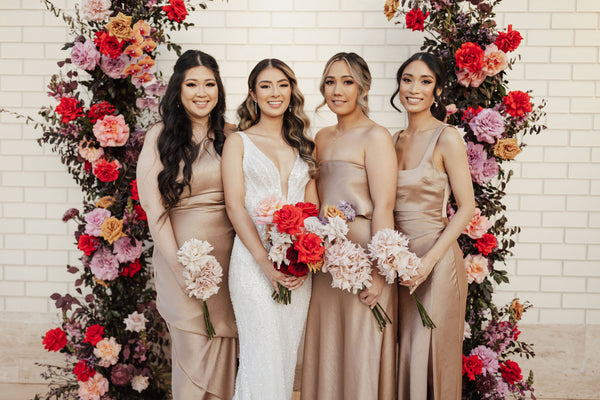 bride and bridesmaids standing in front of floral altar