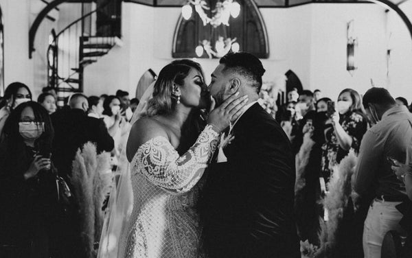 bride and groom kissing in church surrounded by family