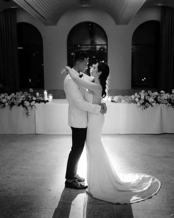 bride and groom sharing their first dance at wedding in front of bridal party table