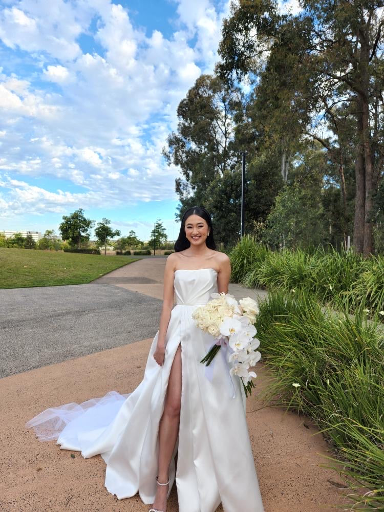 bride in wedding dress holding bouquet at park
