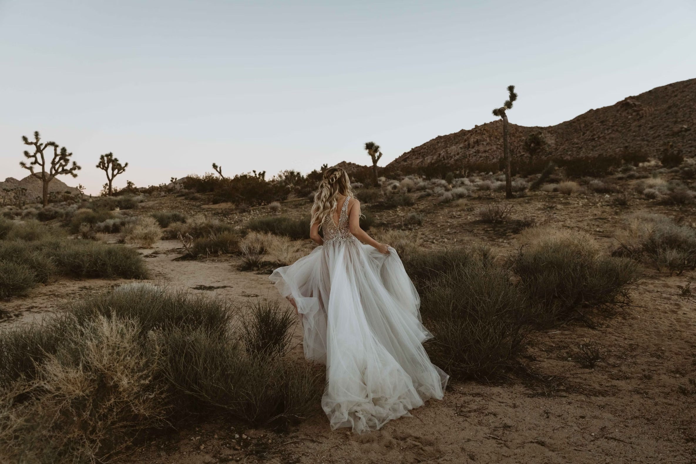 bride in wedding dress walking through desert