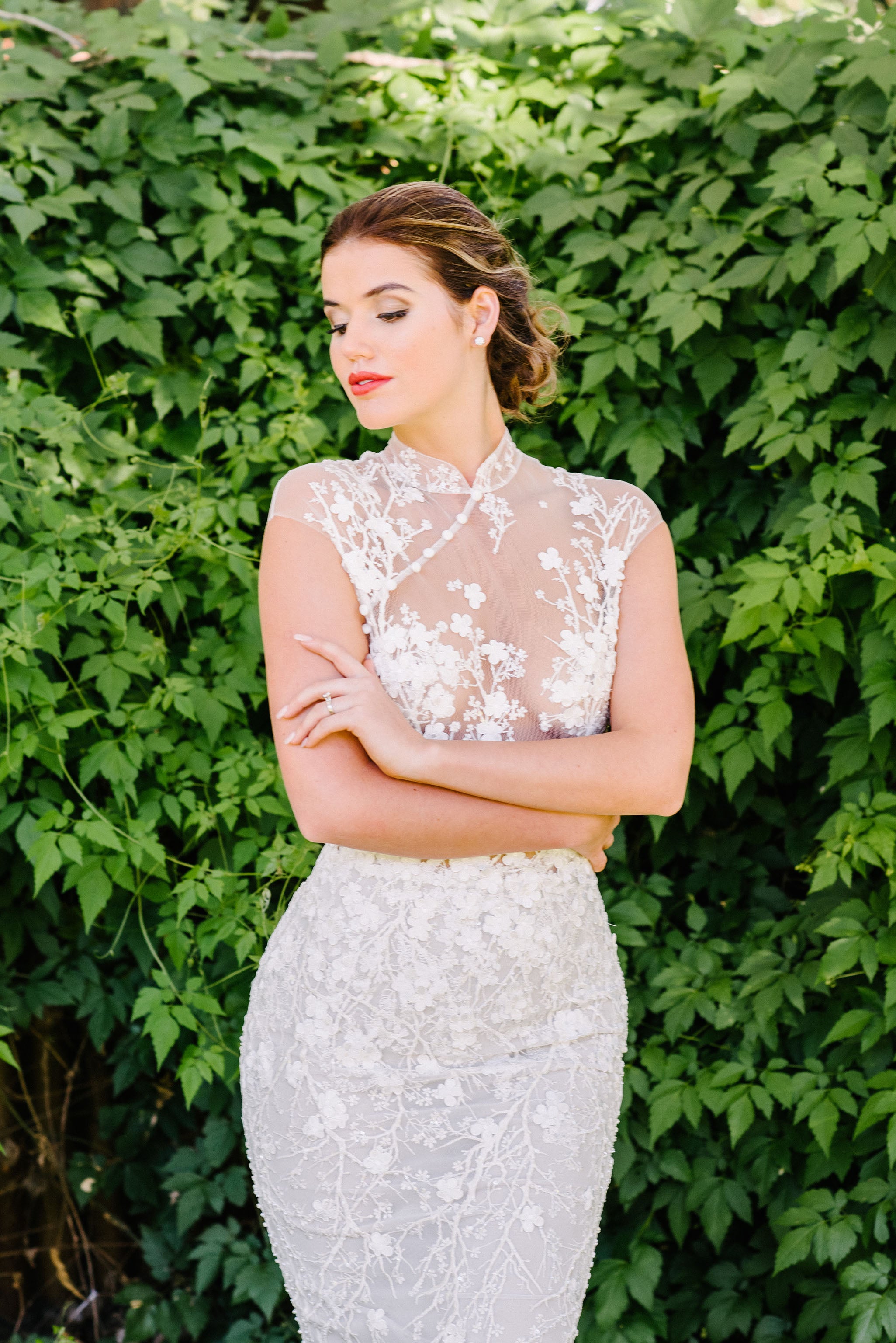 bride posing for wedding photos in front of green bushes