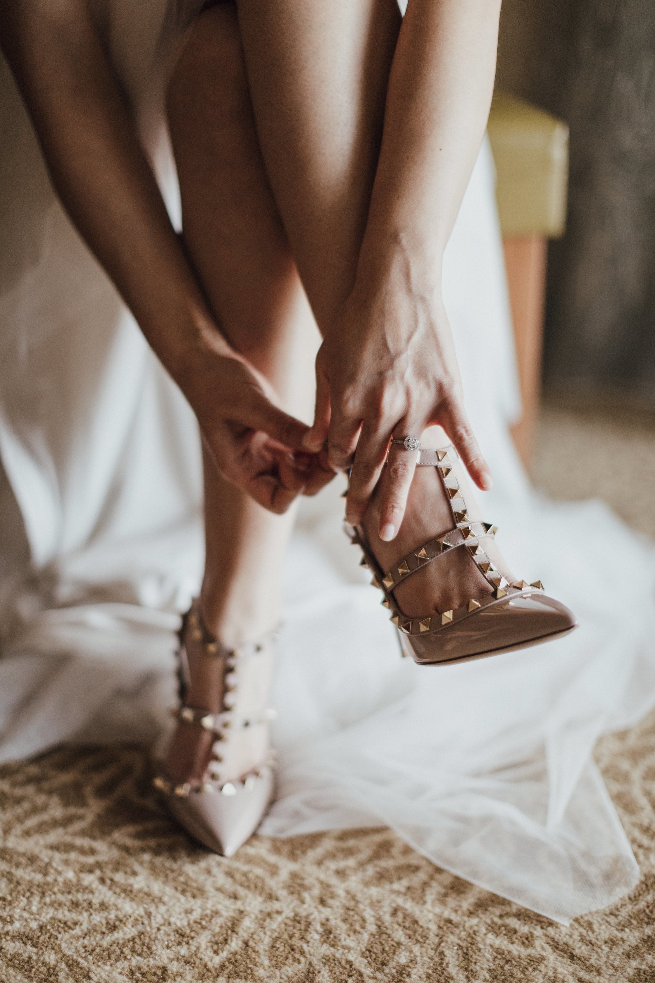 bride tying the straps on her studded wedding heels