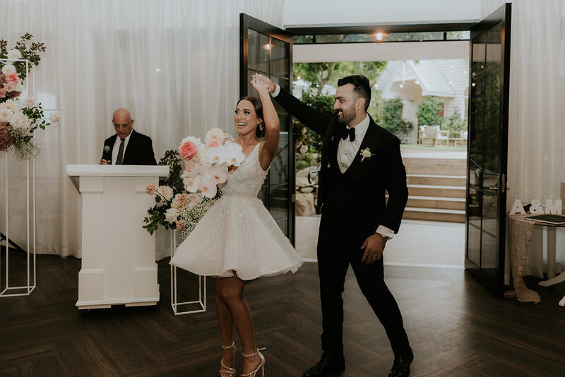 bride wearing mini dress dancing with husband at wedding venue
