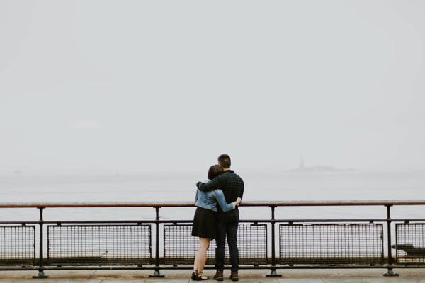 couple embracing looking out over gloomy harbour