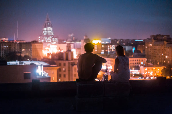 couple sharing wine on rooftop overlooking cityscape