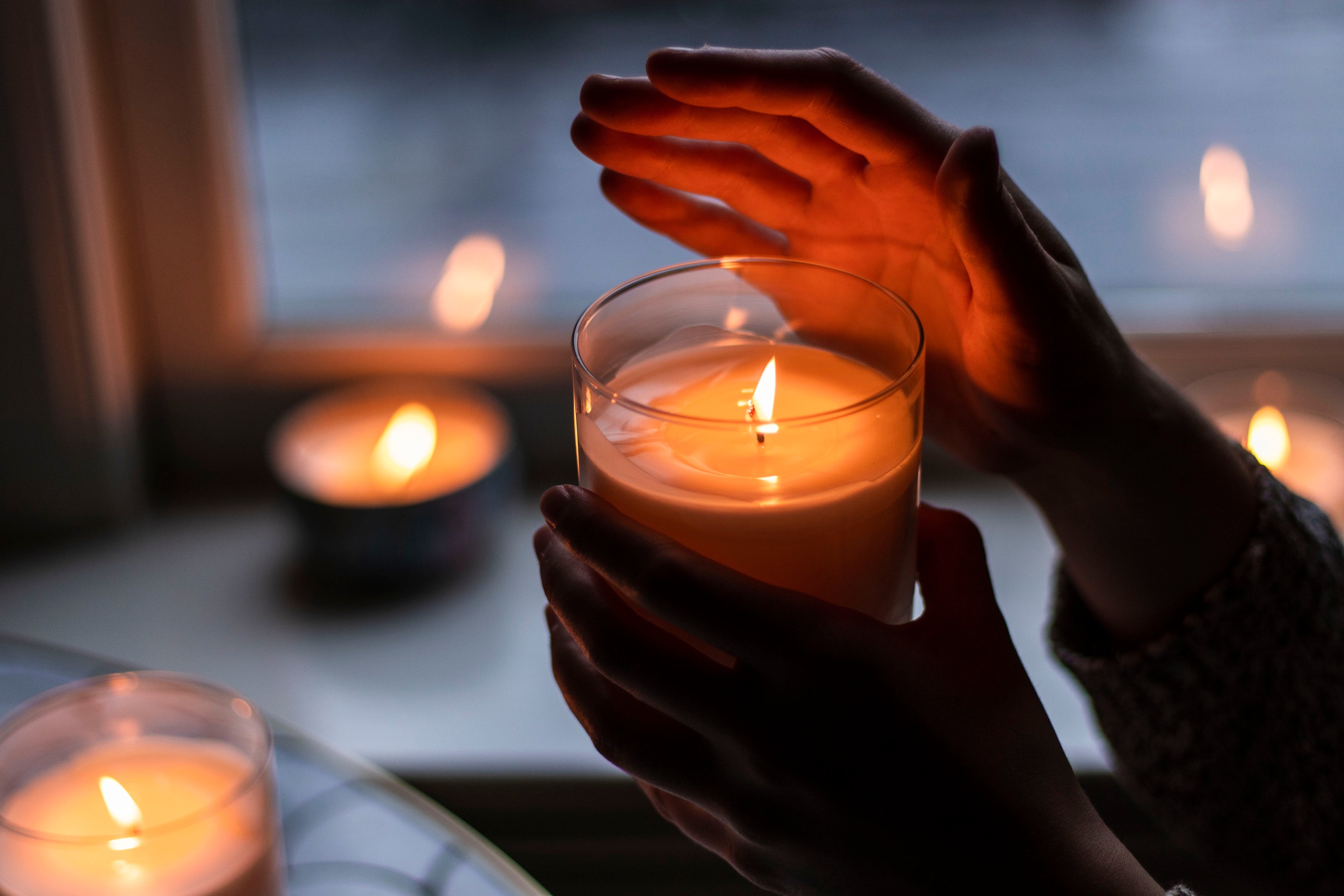hands holding a unity candle at a wedding ceremony with candles burning in background