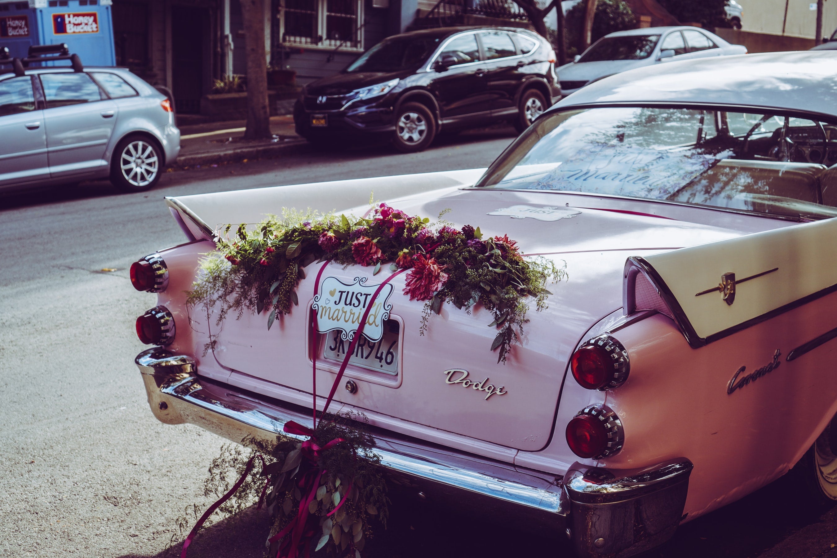 pink car decorated for wedding day with bouquets and just married sign