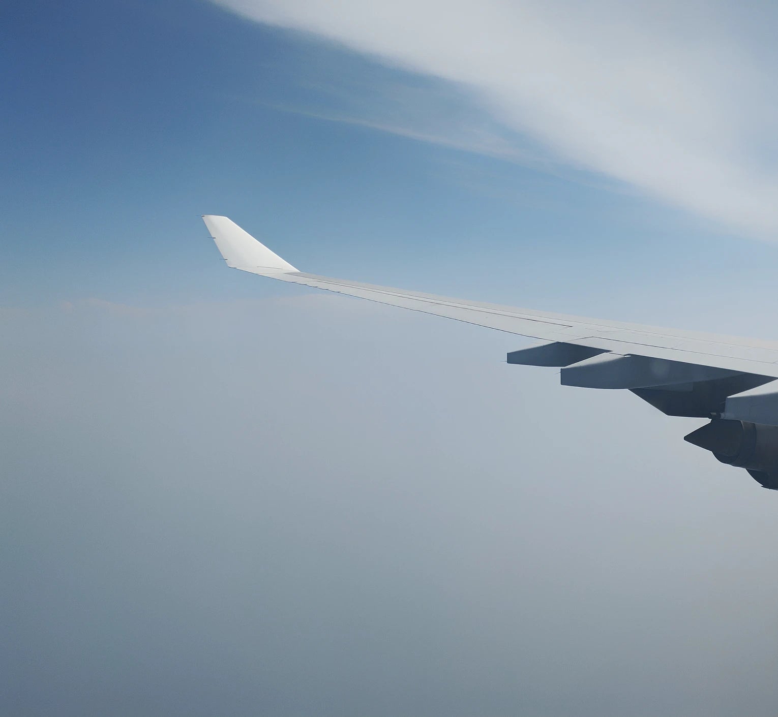 plane wing flying through clouds in the sky
