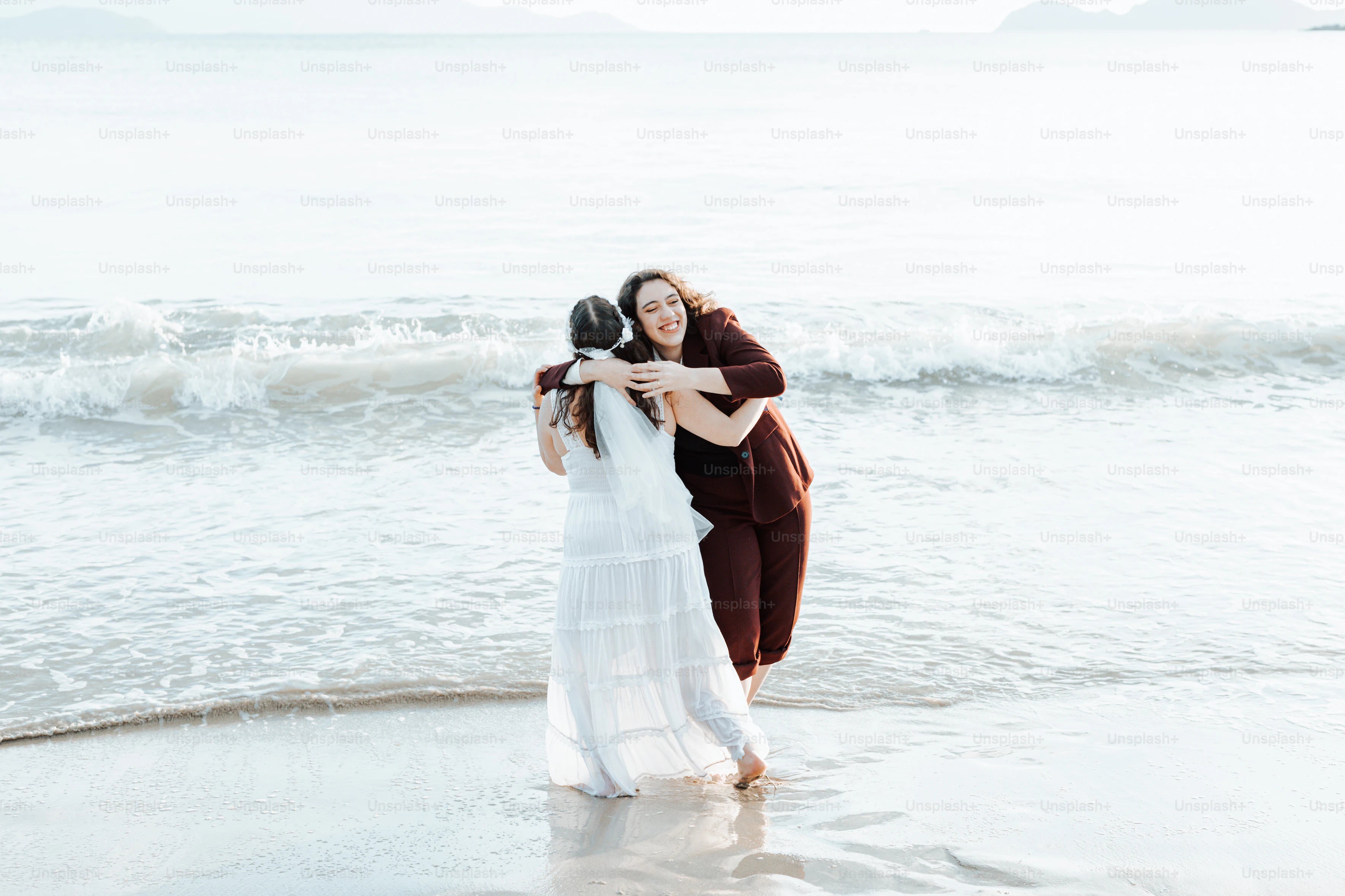two women hugging each other on the beach