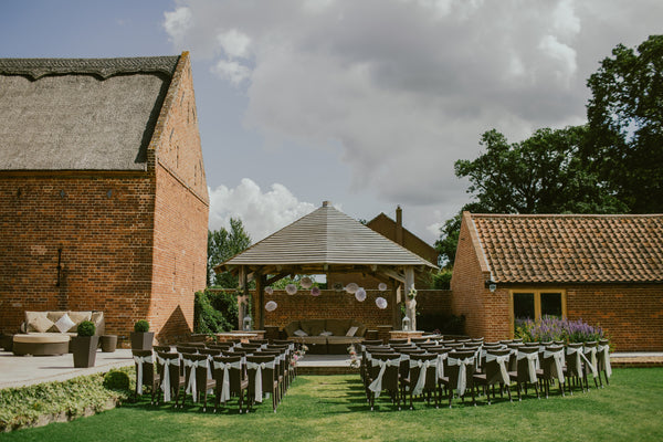 wedding ceremony venue with chairs on grass surrounded by brick buildings