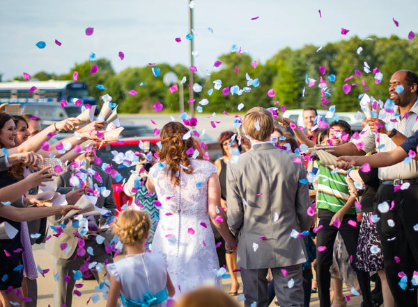 wedding guests throwing confetti on bride and groom
