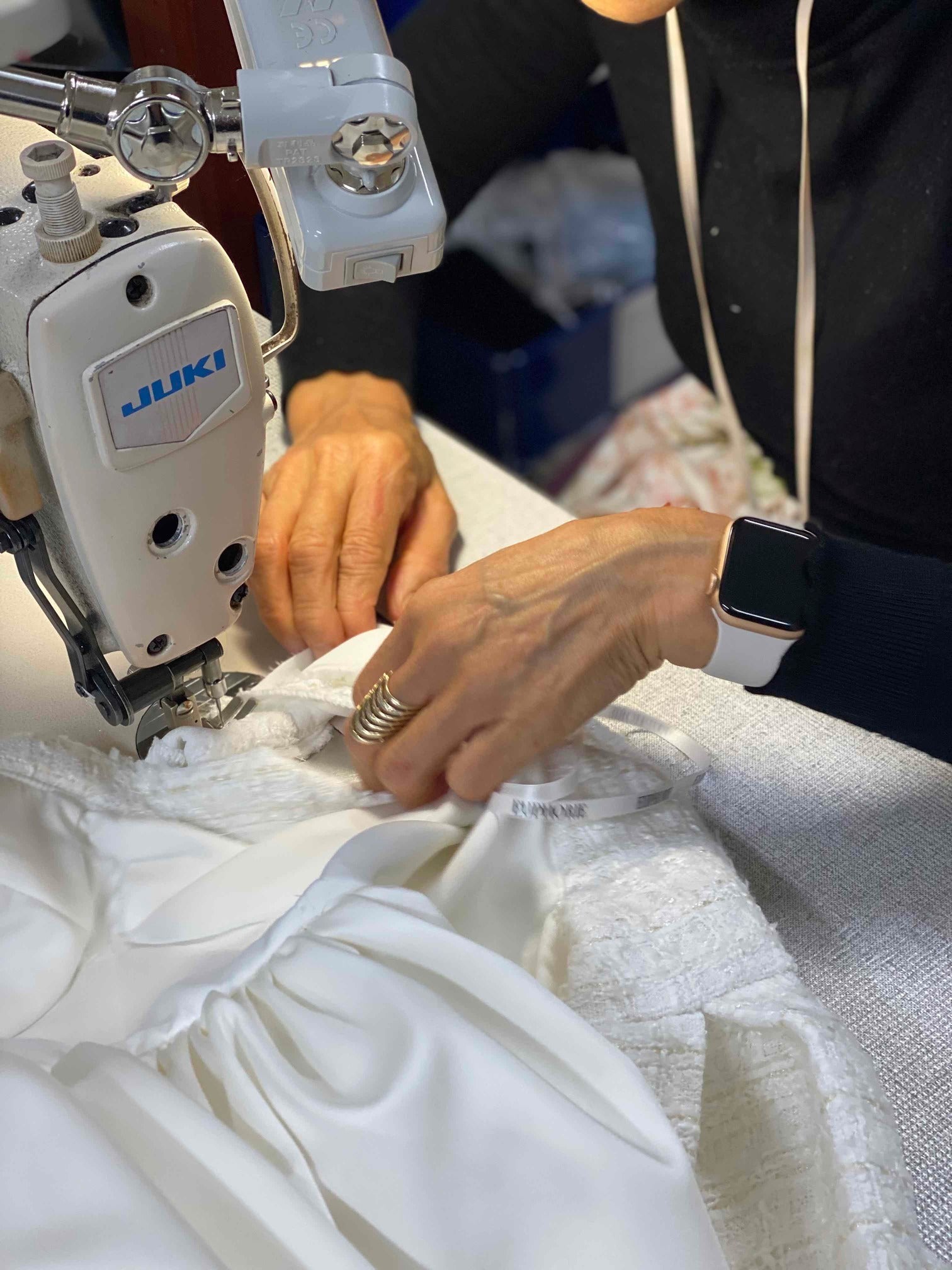womans hands holding fabric next to sewing machine
