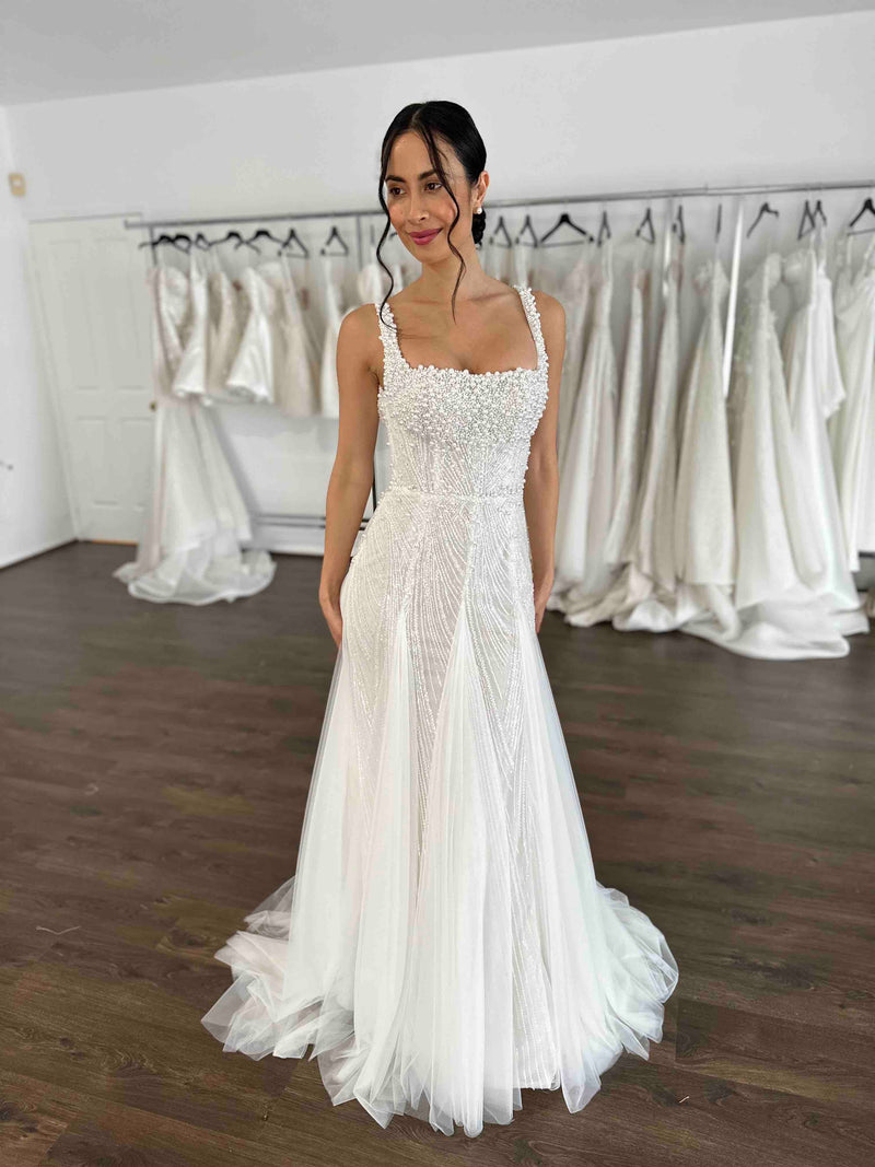 beaded lace wedding gown with pearls and tulle skirt inserts worn by model