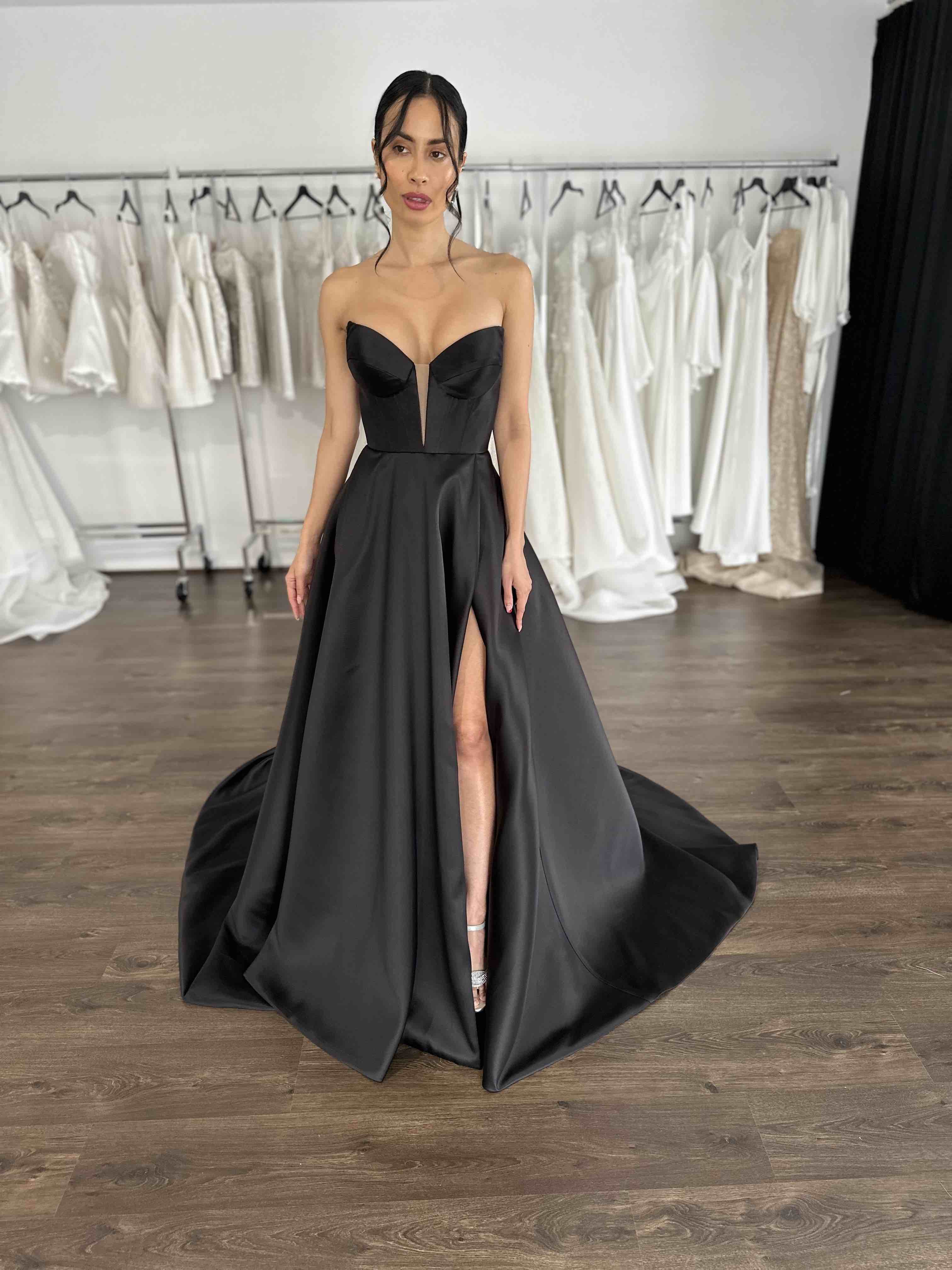black v-neck formal dress with thigh split on model in showroom