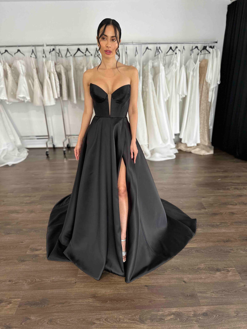 black v-neck formal dress with thigh split on model in showroom