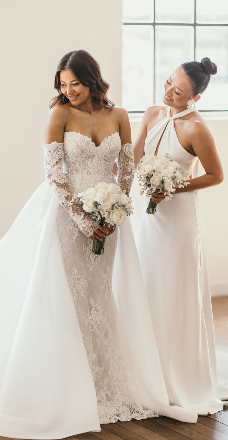 bride with bridesmaid in their wedding attire holding flowers
