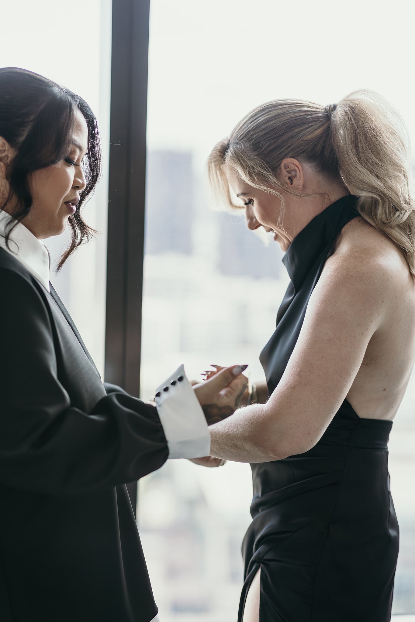 bride helping bridesmaid into black halter neck dress